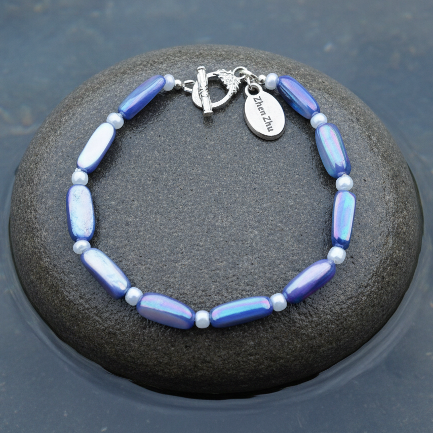 Blauwe parelmoeren armband liggend op steen in water | Shell Stick AB Blue