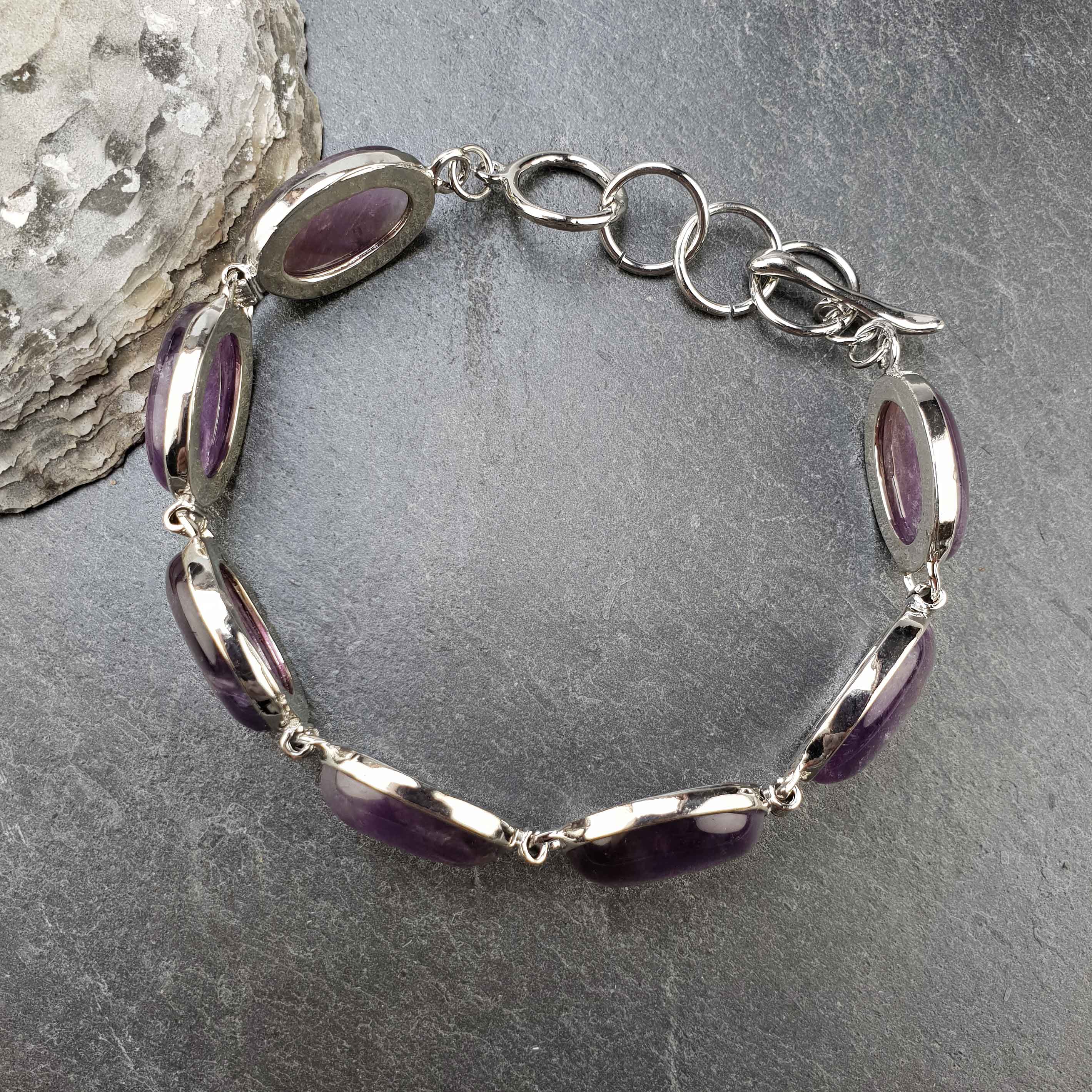 Paarse edelstenen armband met amethist bovenaanzicht liggend op leisteen| Amethyst Oval
