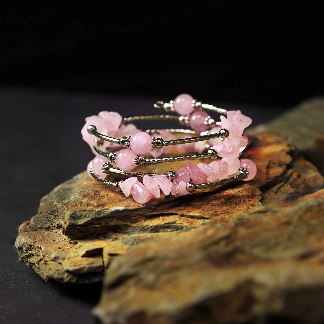 Roze edelstenen wikkelarmband met rozenkwarts liggend op steen | Four Loops Wrap Rose Quartz
