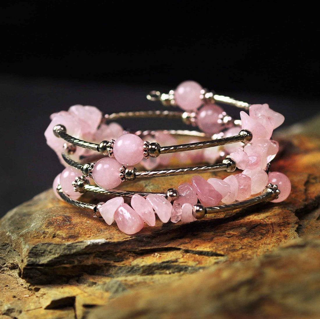 Roze edelstenen wikkelarmband met rozenkwarts liggend op steen | Four Loops Wrap Rose Quartz