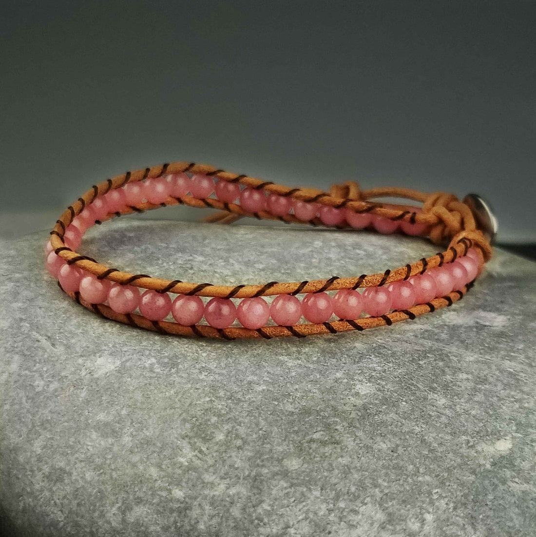 Roze edelstenen armband met rozenkwarts en bruin leer liggend op kei | Wrap Little Rose Quartz