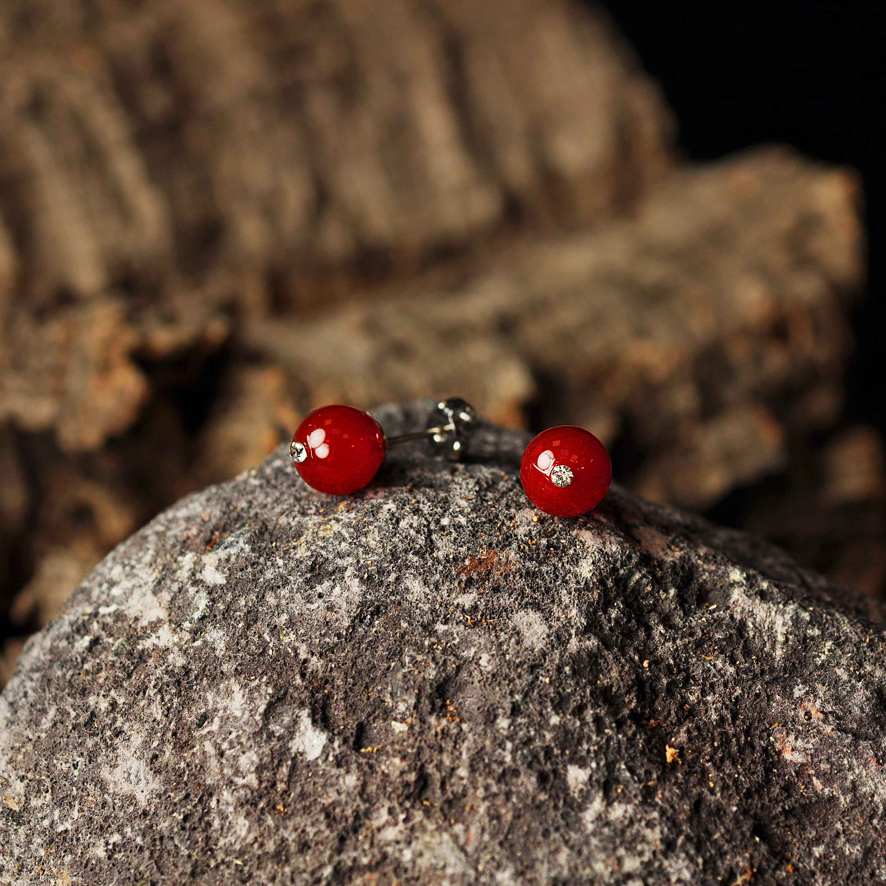 Rode edelstenen oorbellen met agaat, rode edelstenen oorknopjes liggend op zwarte steen | Bling Red Agate