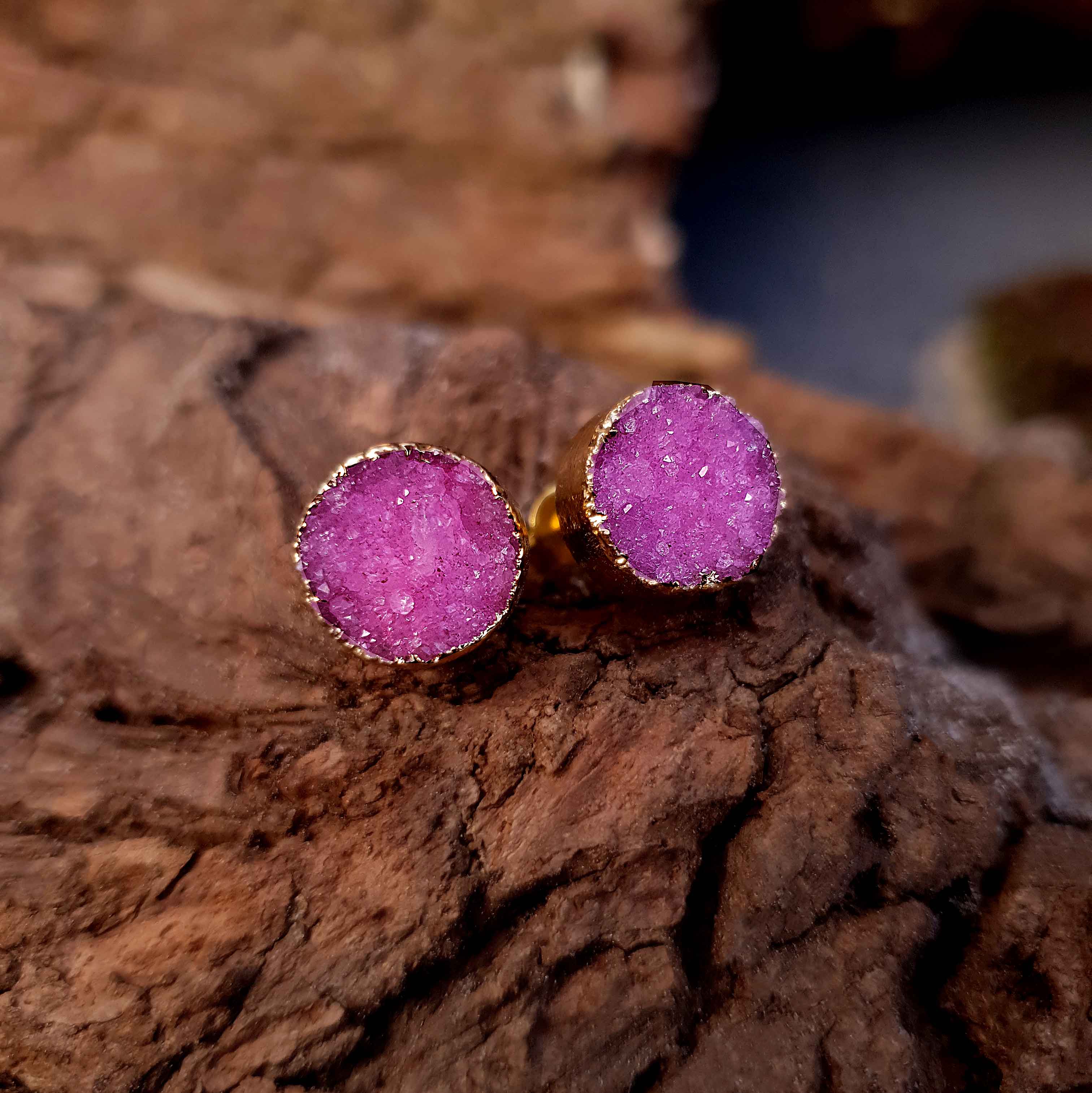 Edelstenen oorknoppen met roze druzy agaat en goud vooraanzicht liggend op hout | Druzy Gold Fuchsia