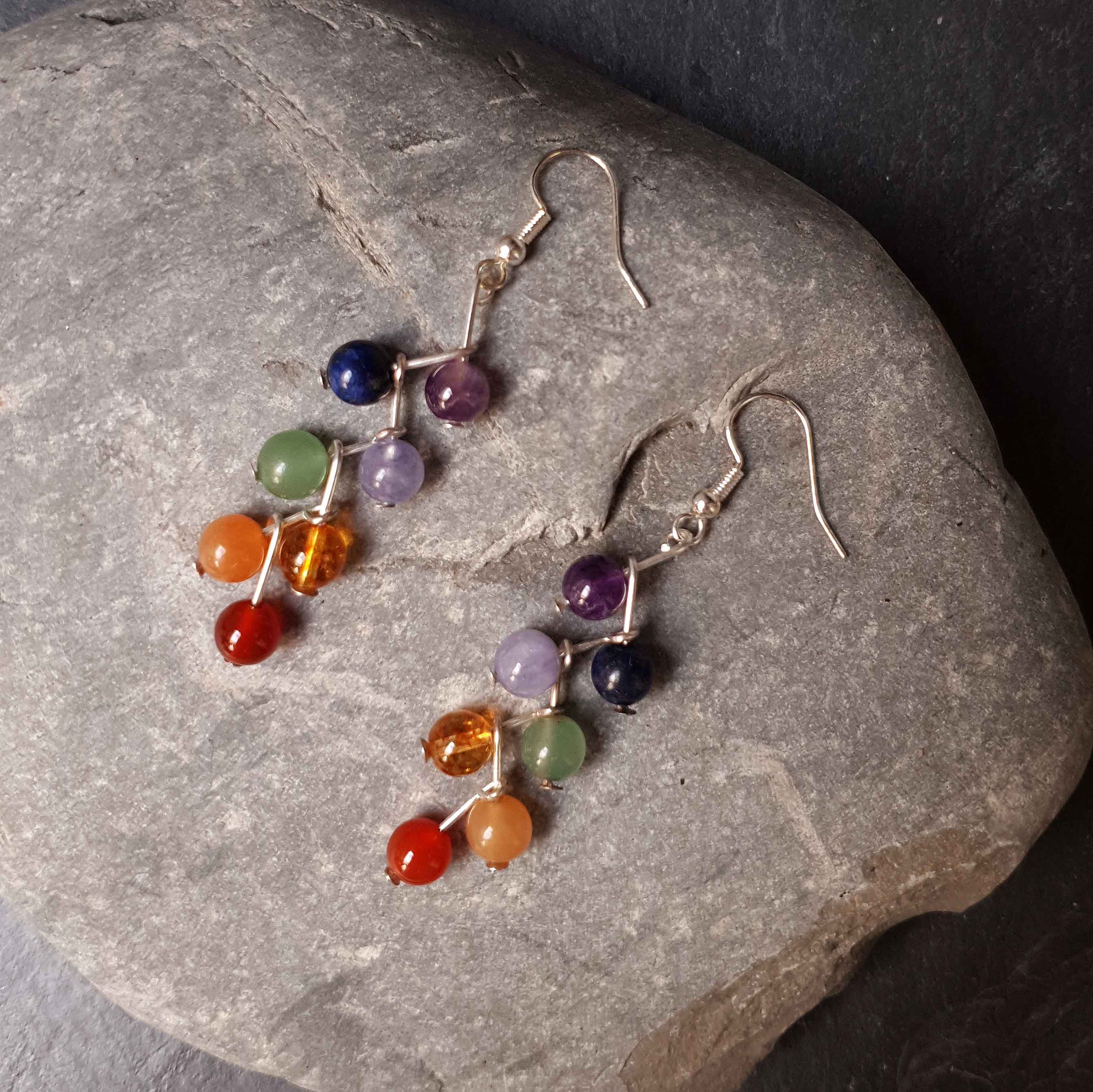 Edelstenen oorbellen met verschillende kleuren edelstenen en sterling zilver liggend op steen | Gemstone Rainbow