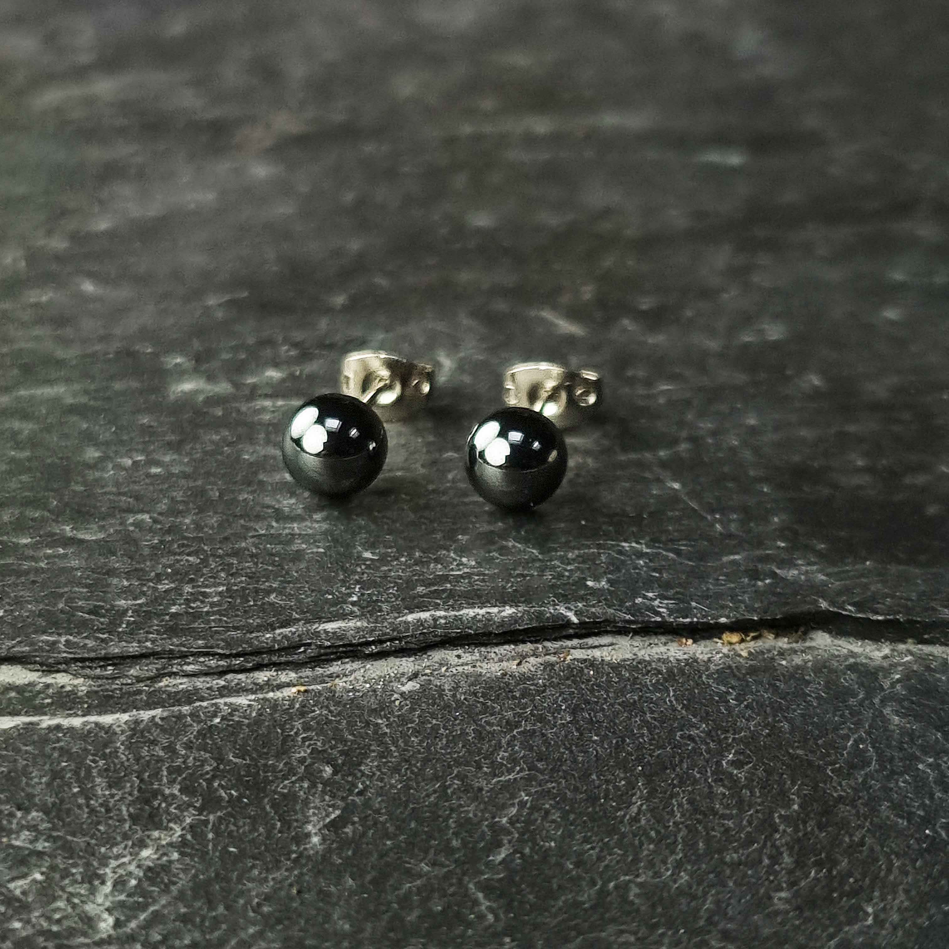 Zwarte edelstenen oorbellen met hematiet stenen liggend op leisteen, zwarte hematiet oorknopjes 6 mm liggend op leisteen | hematite Stud 6 mm