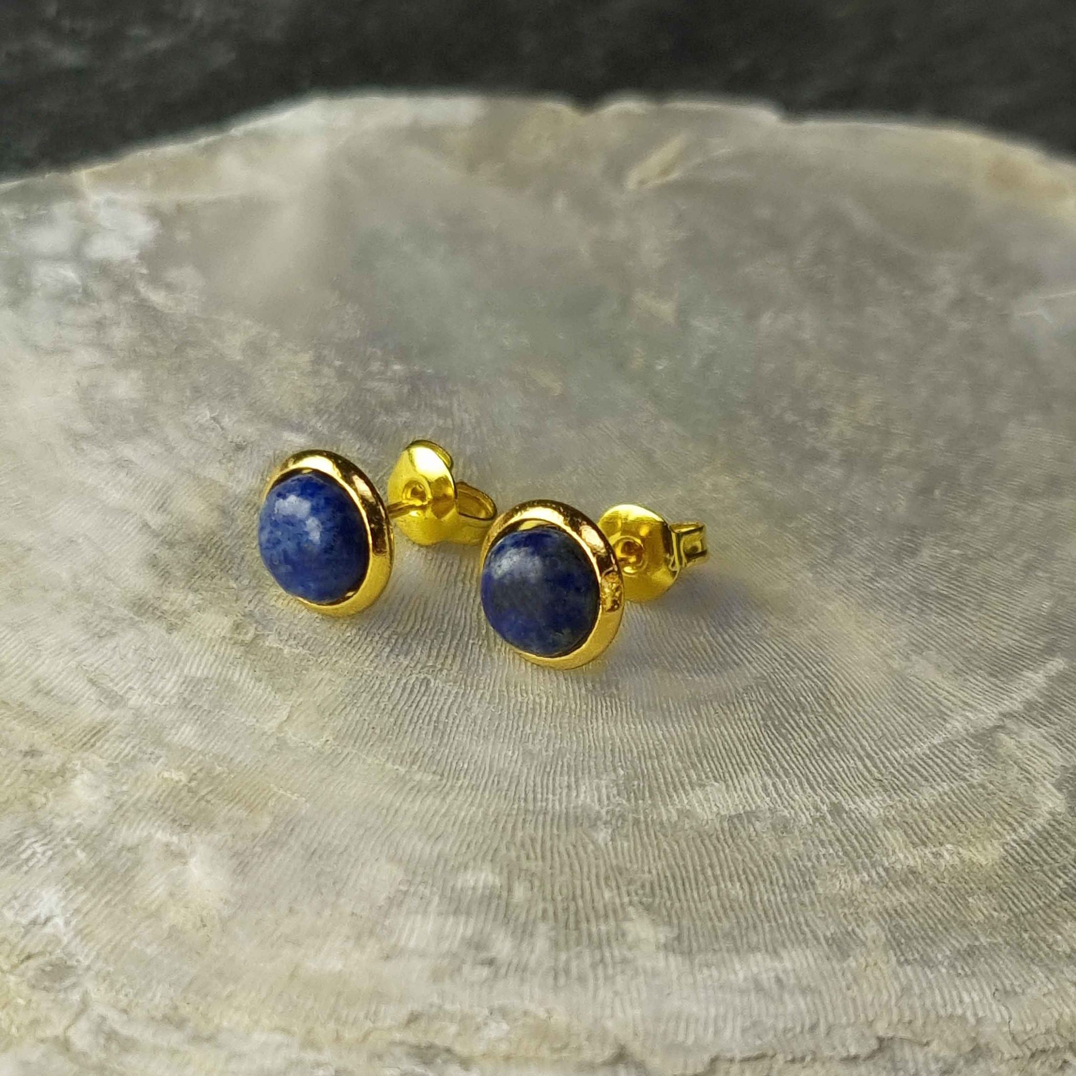 Blauwe edelstenen oorbellen met lapis lazuli, lapis lazuli oorknopjes liggend op witte schelp, vooraanzicht | Lapis Lazuli Small Gold