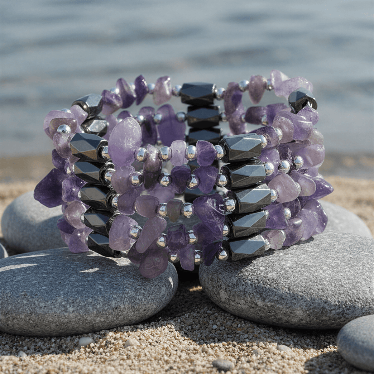 Paarse edelstenen armband met amethist en magnetiet liggend op steen aan waterrand | Wrap Magnetite Amethyst