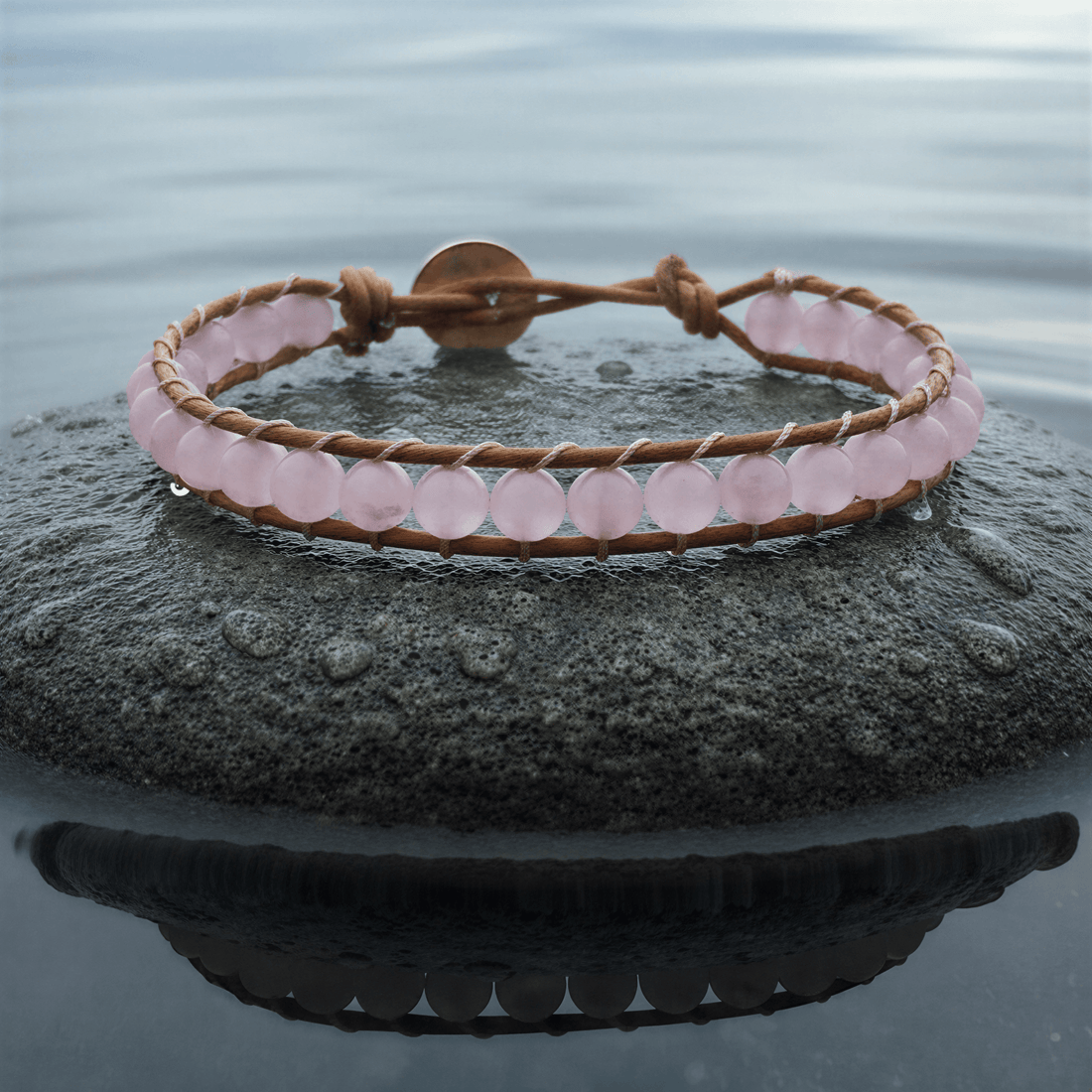 Roze edelstenen armband met rozenkwarts en licht bruin leer liggend op steen | Wrap Rose Quartz Light