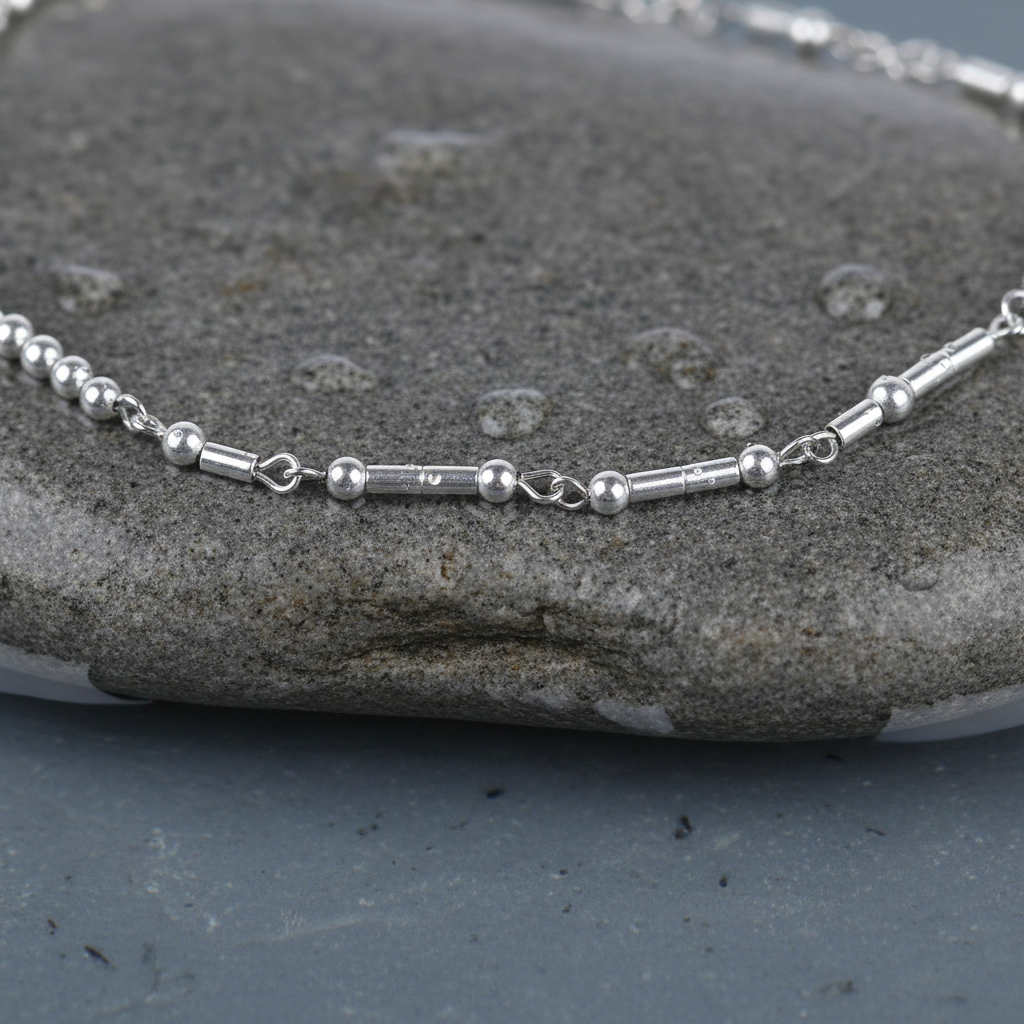 Zilveren edelstenen ketting met zilver edelstaal en hematiet stenen die het woord HAPPY in morse code weer geeft liggend op steen close up | Morse Code Happy Silver Hematite