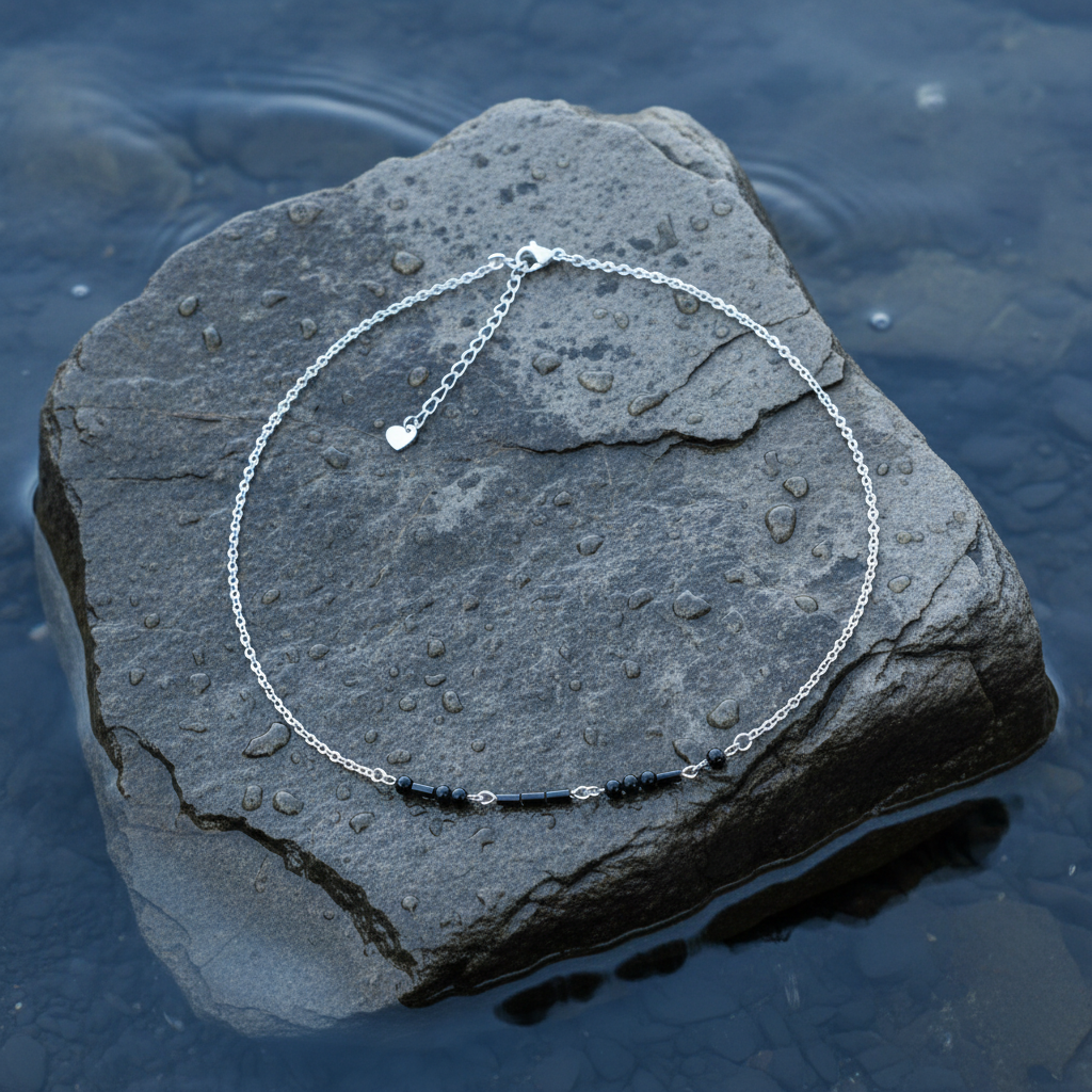 Zwarte edelstenen ketting met zilver edelstaal en hematiet stenen die het woord LOVE in morse code weer geeft liggend op steen in water | Morse Code Love Black Hematite Silver