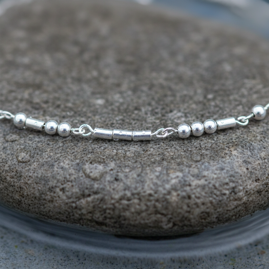 Zilveren edelstenen ketting met zilver edelstaal en hematiet stenen die het woord LOVE in morse code weer geeft liggend op steen close up | Morse Code Love Silver