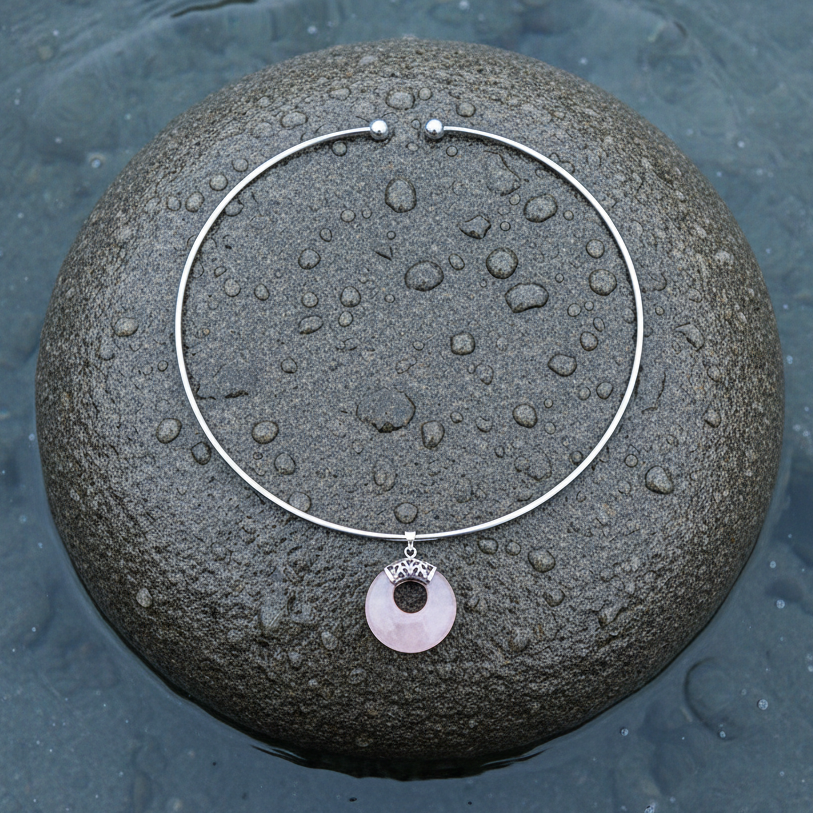 roze edelstenen ketting met rozenkwarts in vorm van donut liggend op steen in water | Rosé Quartz Donut