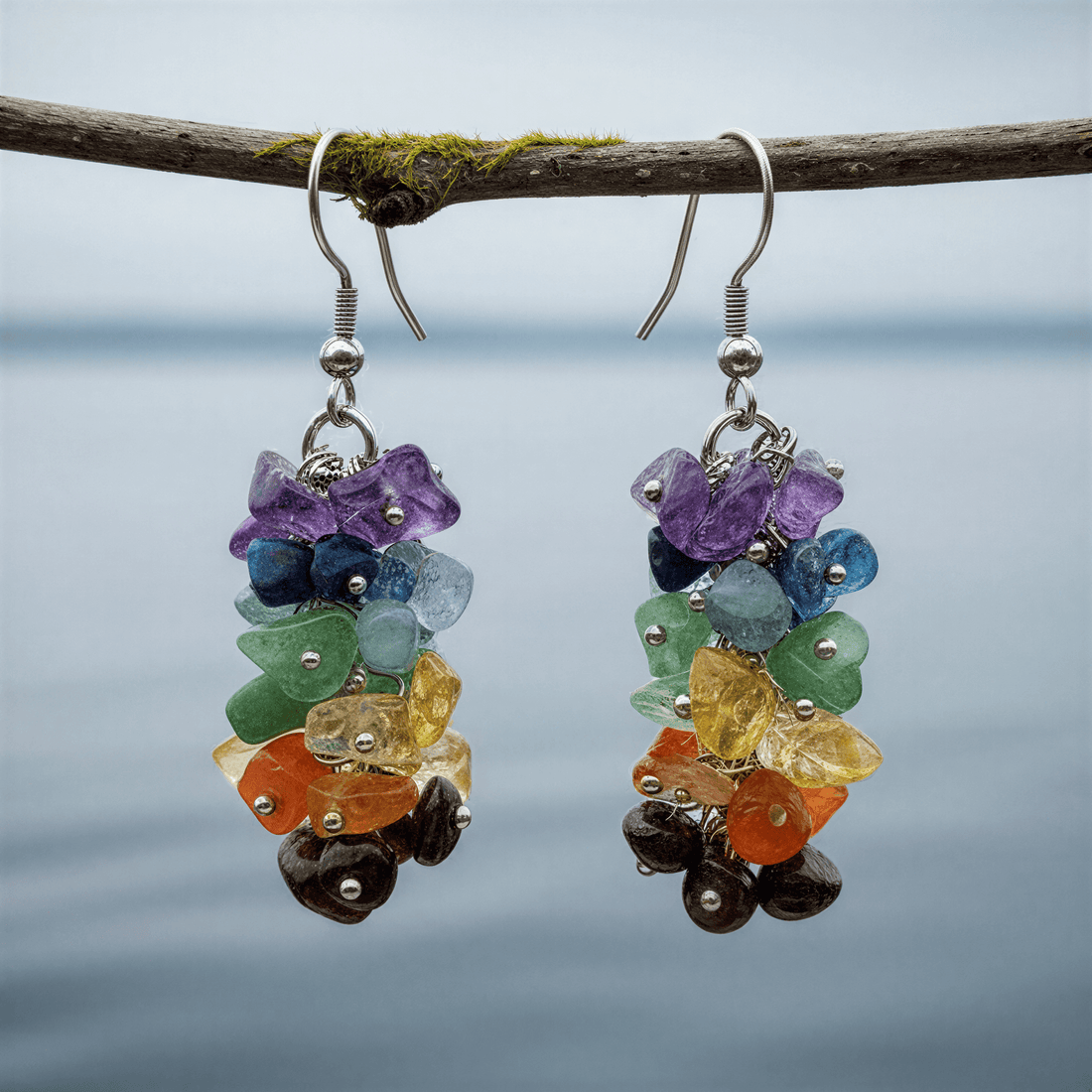 Edelstenen oorbellen met veel gekleurde edelstenen en zilver edelstaal hangend aan takje boven water| Gemstone Chips