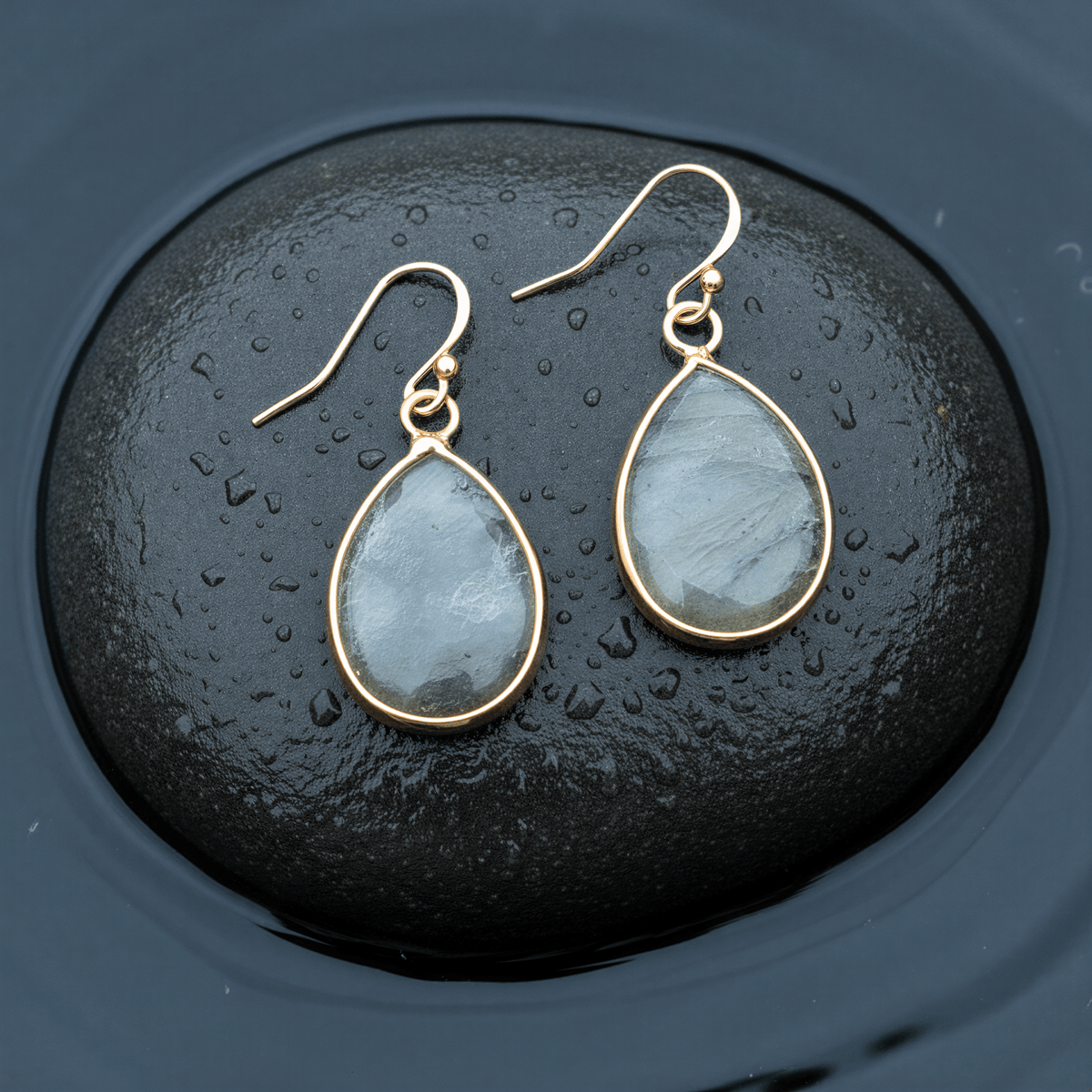 Edelstenen oorbellen met labradoriet in druppel vorm en goud edelstaal liggend op natte steen | Labradorite Small Teardrop