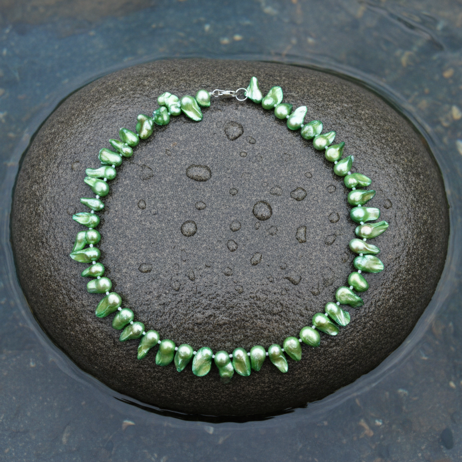 Handgeknoopte zoetwater parelketting met groene parels en sterling zilver (925) liggend op steen in water | Green Blister