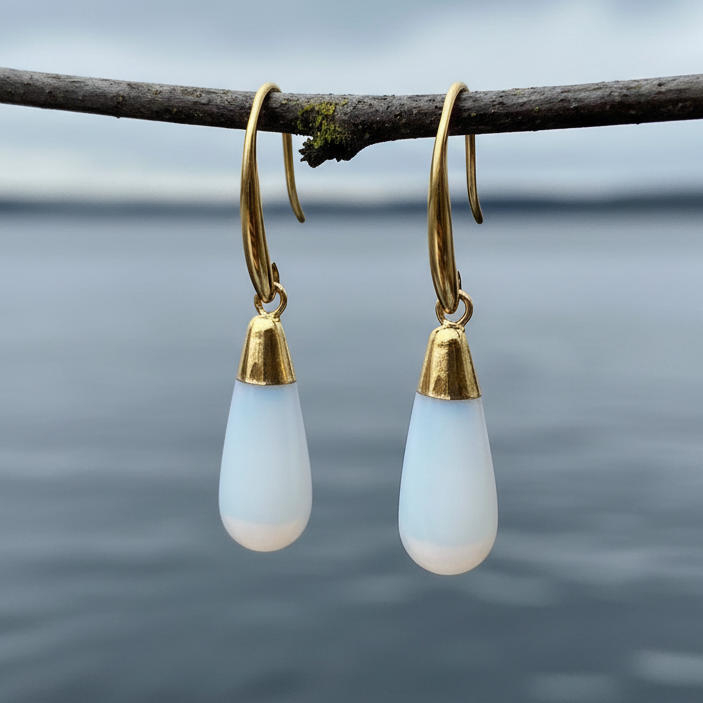 Licht blauwe edelsten oorbellen met opaal hangend aan takje boven water | Long Gold Dip Sea Opal