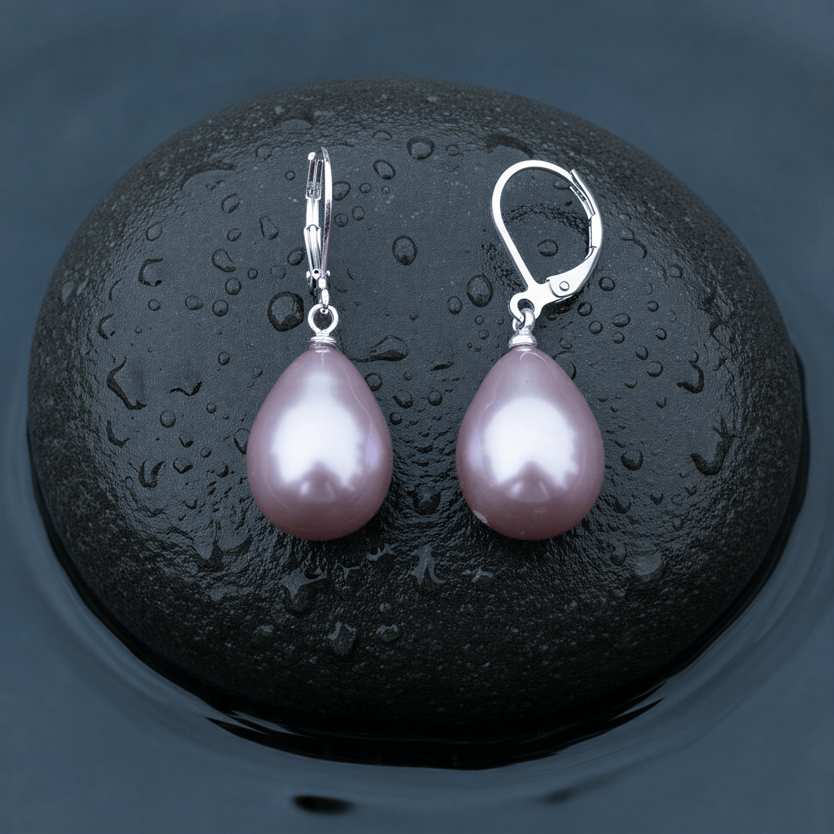 Roze mother of pearl parel oorbellen met zilver edelstaal liggend op steen in water | Holly