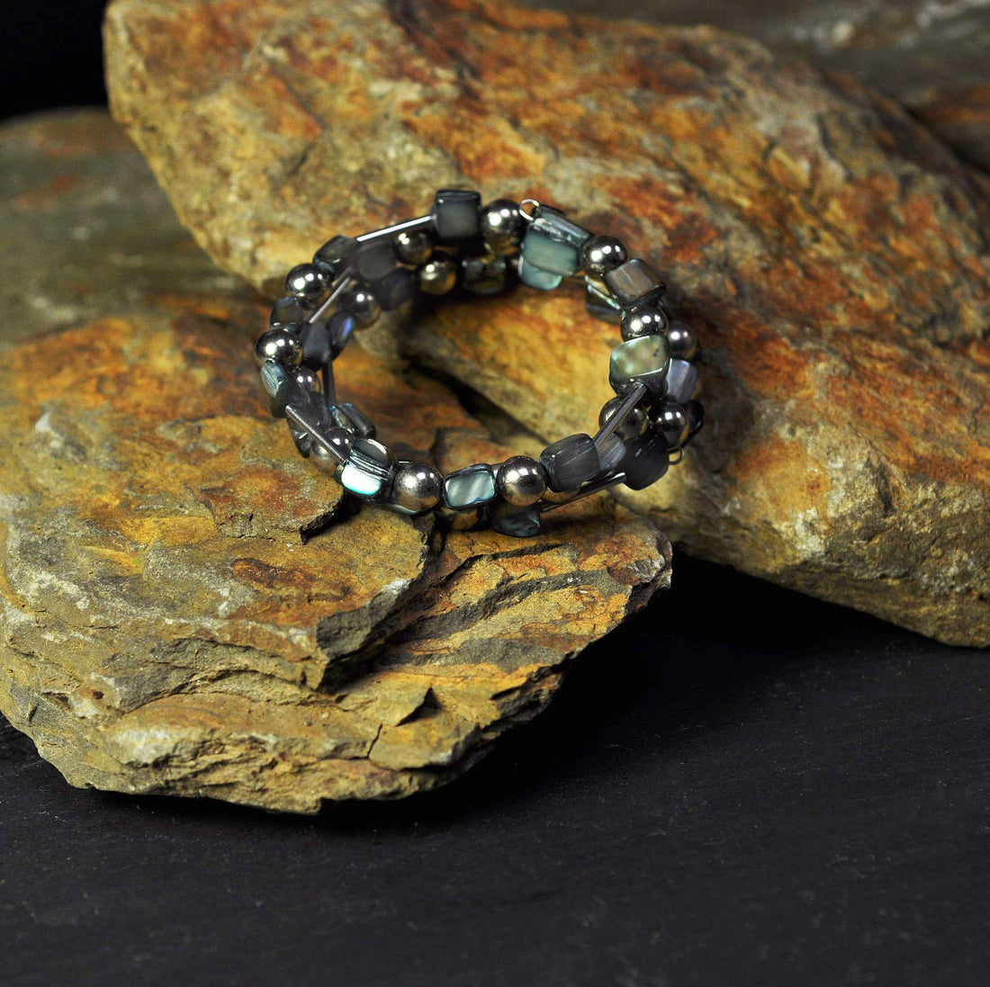 Grijs parelmoeren wikkelarmband liggend op steen | Wrap Shell Grey