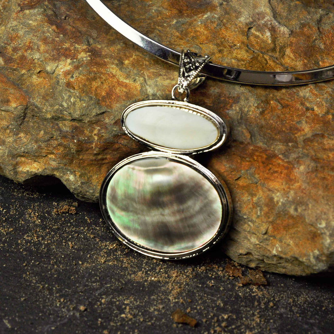 Detail van parelmoeren ketting met hanger liggend tegen steen | Black & White Shell