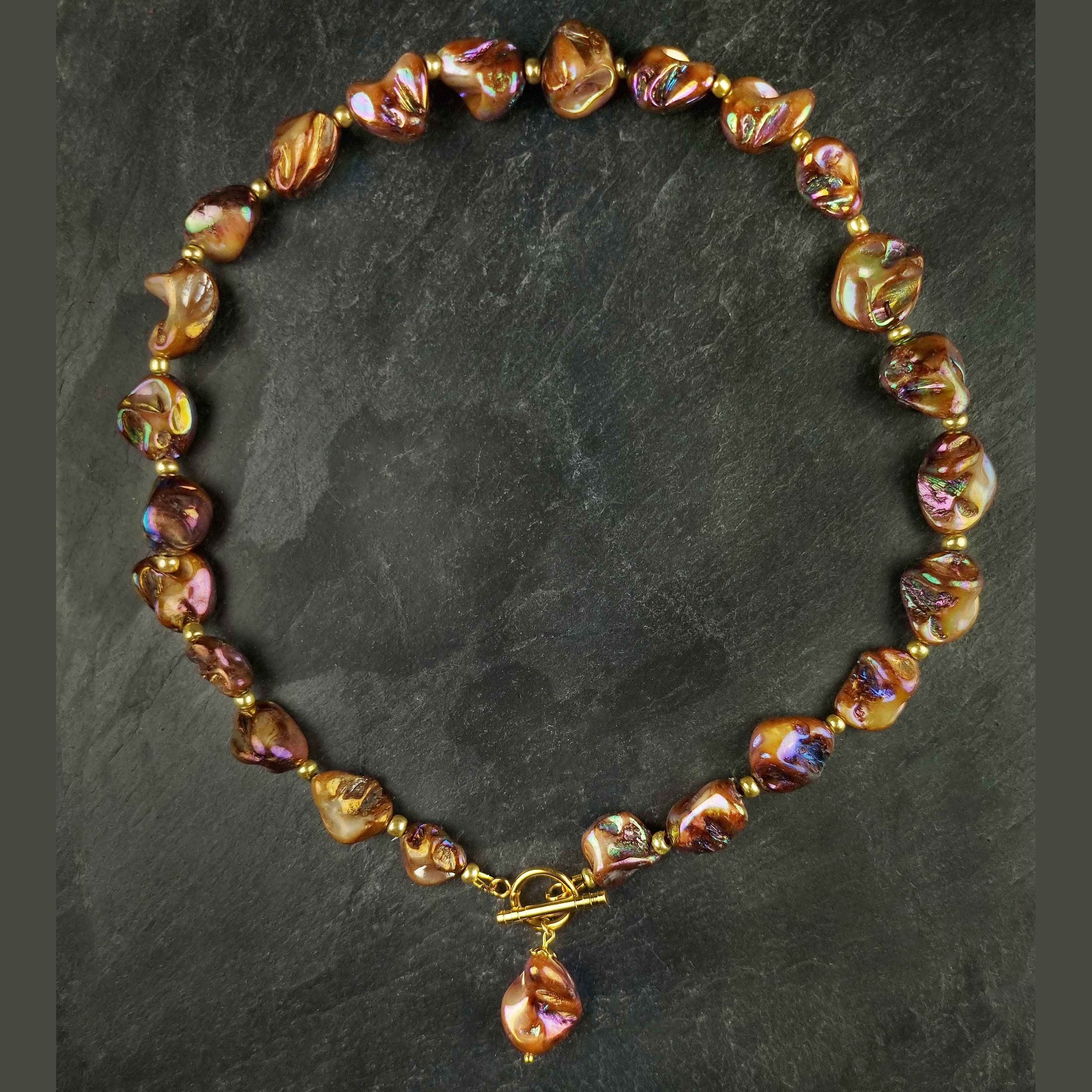 Bruin gekleurde parelmoeren schelpen ketting en goud edelstaal liggend op leisteen | set Shell AB Brown Gold