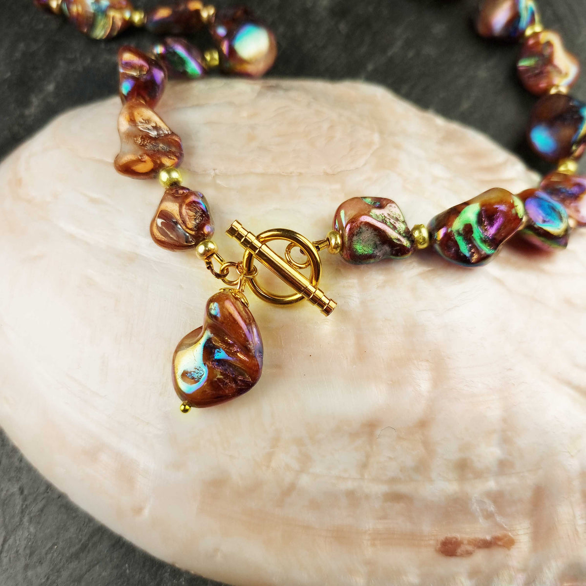 Slotje van bruin gekleurde parelmoeren schelpen ketting en goud edelstaal liggend op schelp | set Shell AB Brown Gold