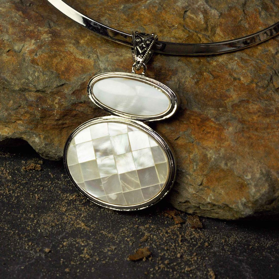 Detail van Parelmoeren ketting met witte hanger liggend tegen steen | White & Mosaic Shell