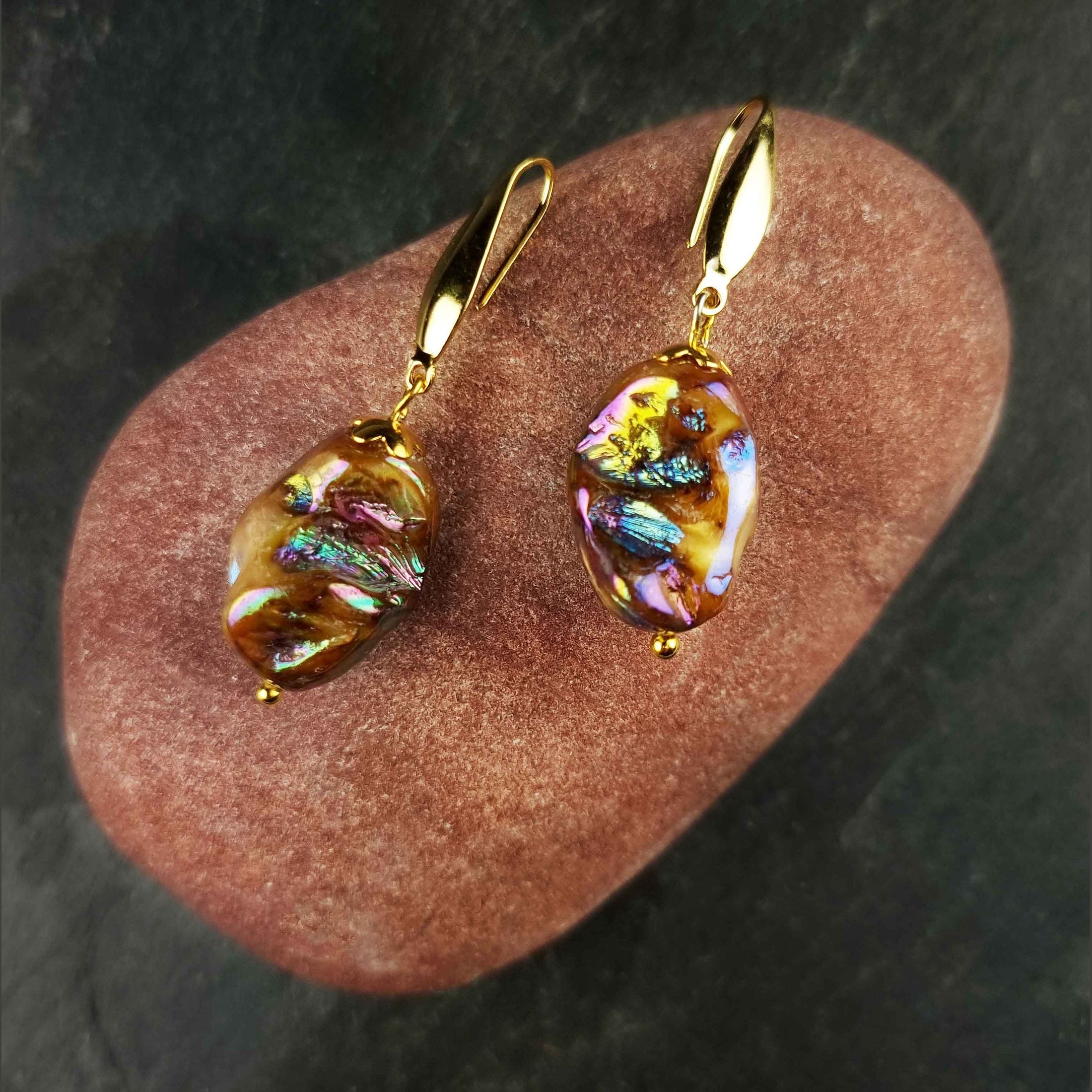 Bruin gekleurde parelmoeren schelpen oorbellen met goud edelstaal liggend op rode steen | set Shell AB Brown Gold