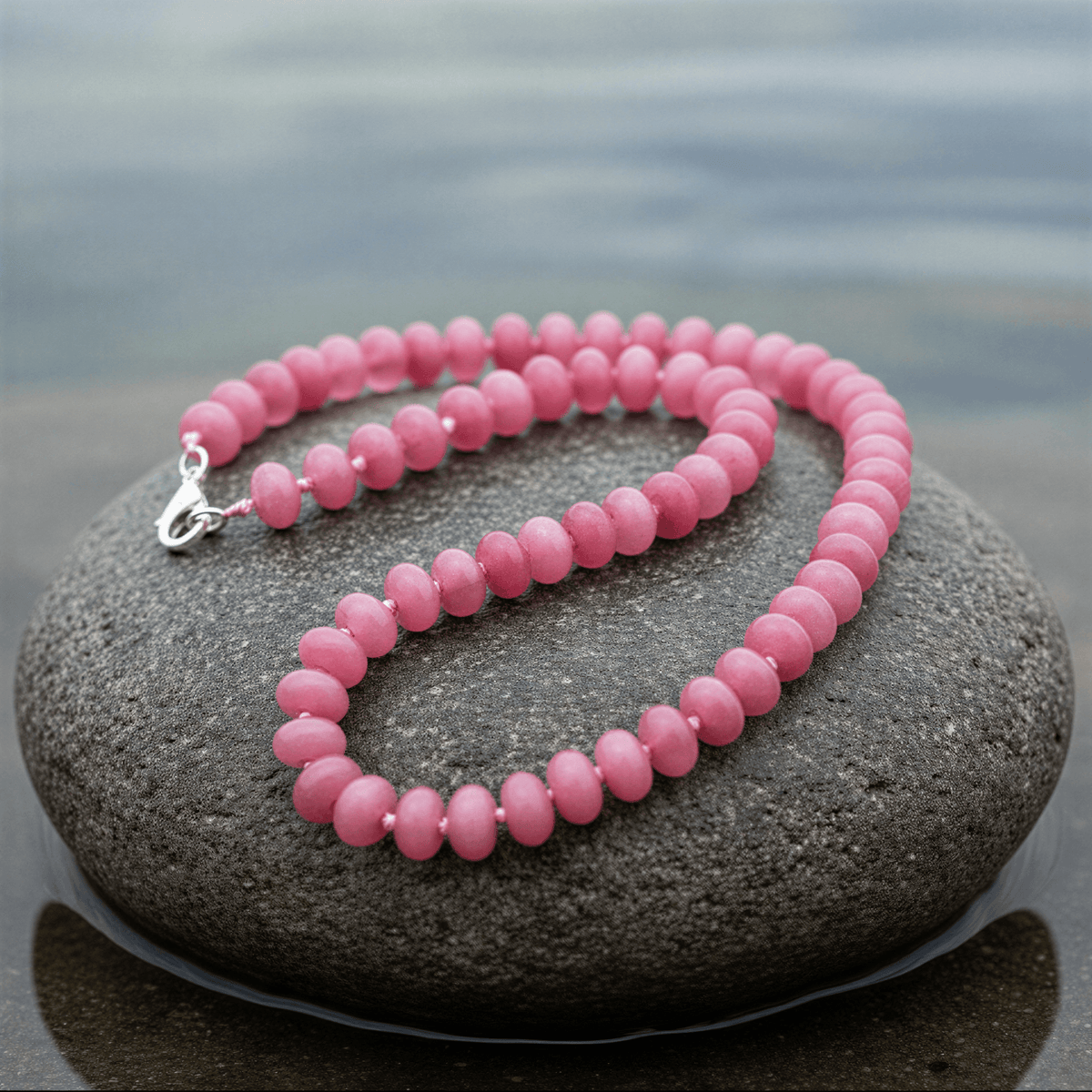 Roze handgeknoopte edelstenen ketting met sterling zilver (925) liggend op steen close up | Cherry Quartz Rondelle