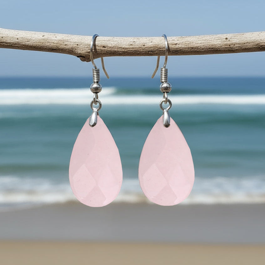 Roze edelstenen oorbellen met rozenkwarts en sterling zilver 925 hangend aan takje met achtergrond zee | Facet Rosé Quartz