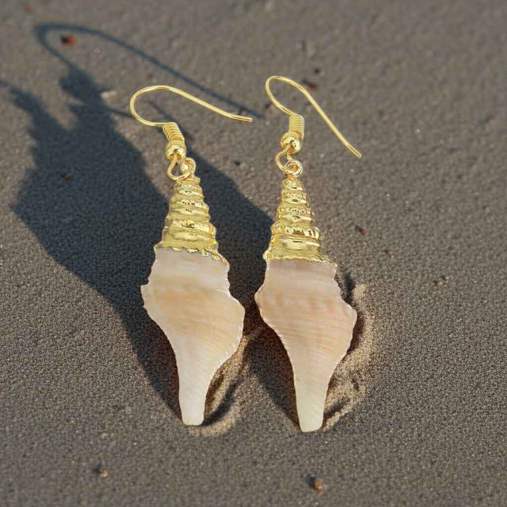 Schelpen oorbellen met crème kleurige schelp en goud edelstaal liggend op strand | Beige Tower Shell