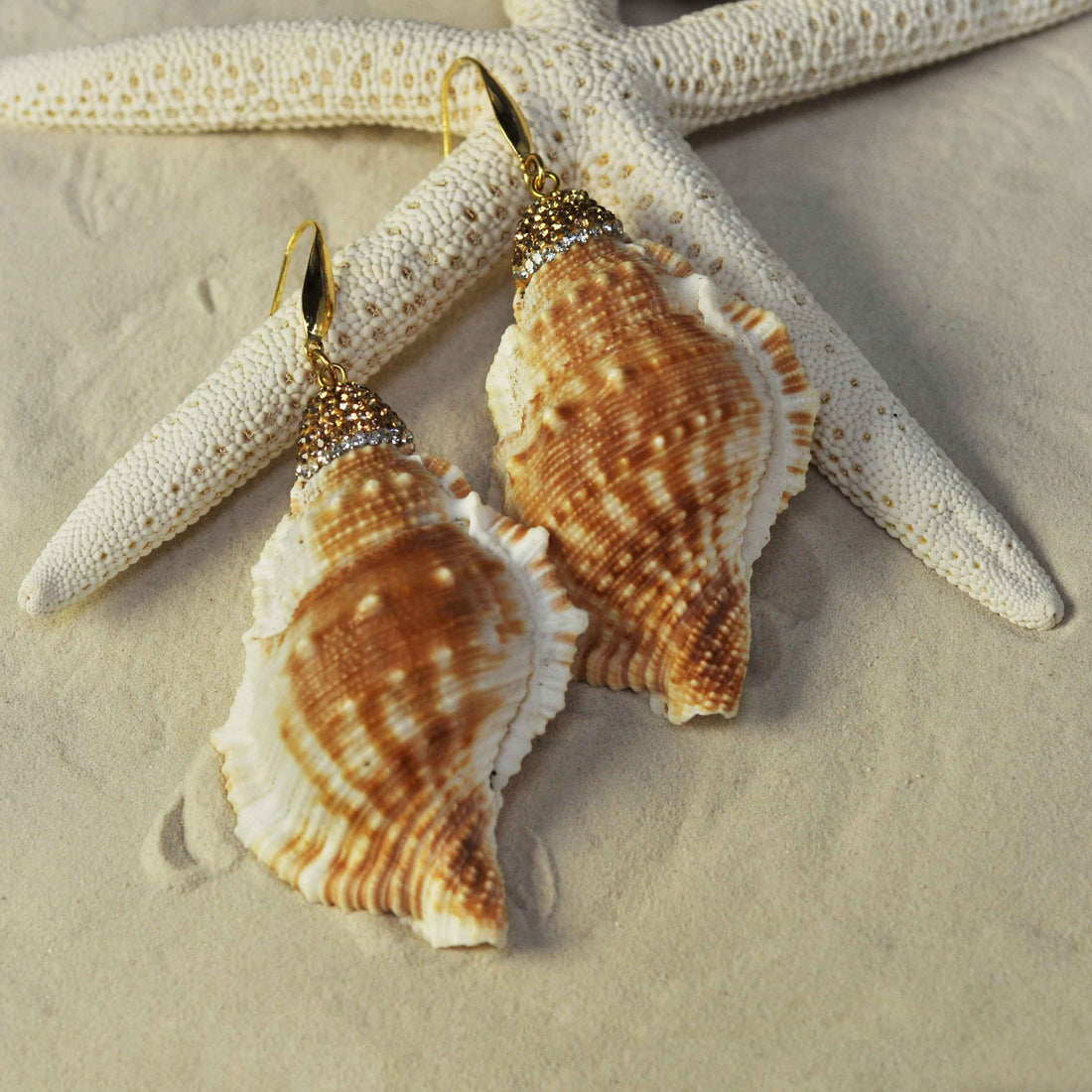 Grote licht gewicht schelpen oorbellen met goud edelstaal liggend op strand | Bright Golden Spiral Shell