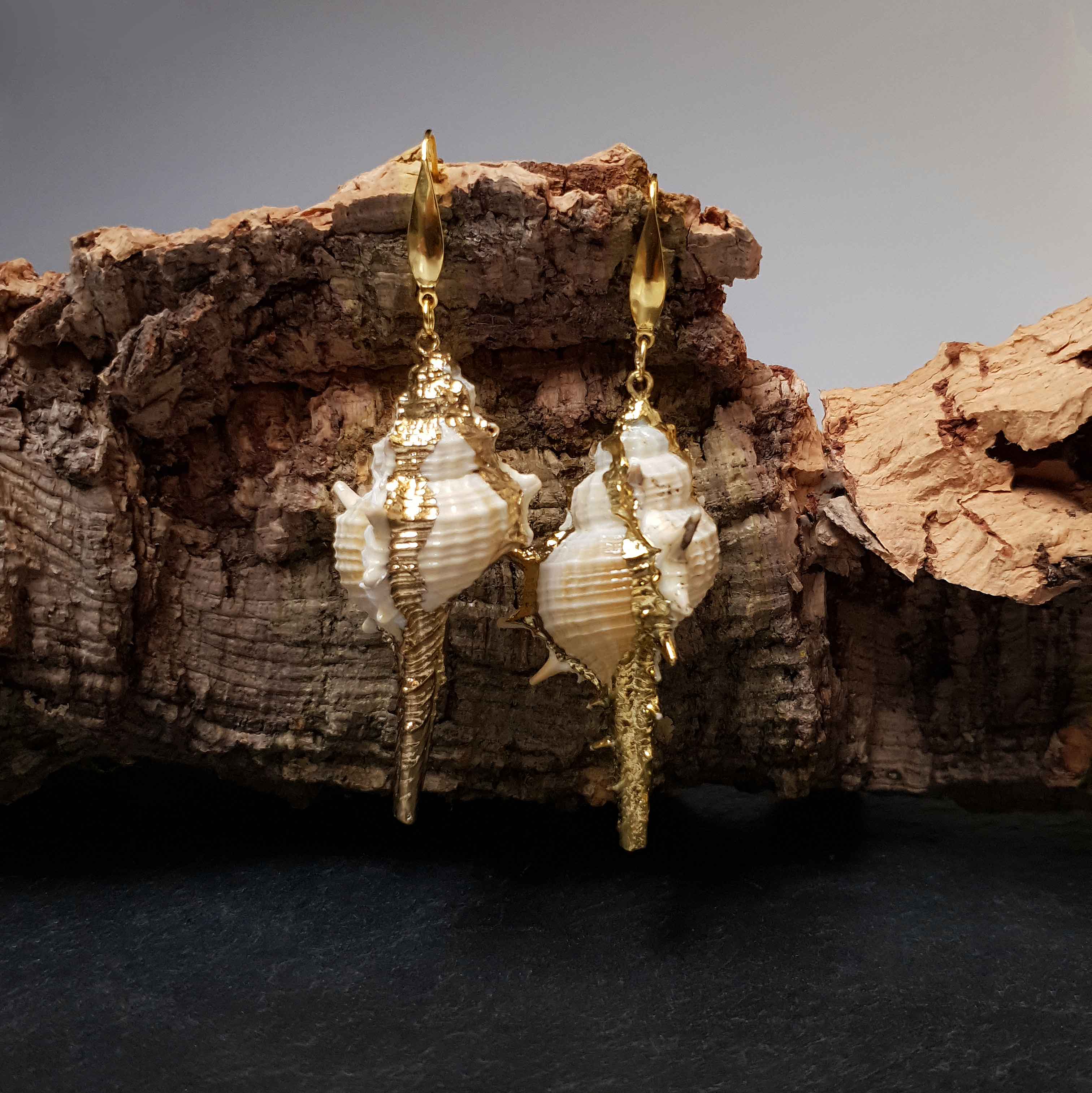 Lange schelpen oorbellen met witte schelp en goud edelstaal hangend aan hout | Shell Cabrit Gold