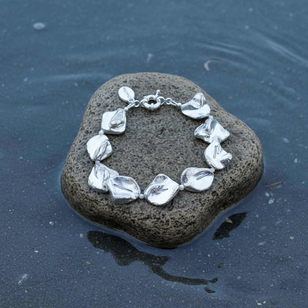 Zilver kleurige parelmoer schelpen armband liggend op steen in water | Shell Silver