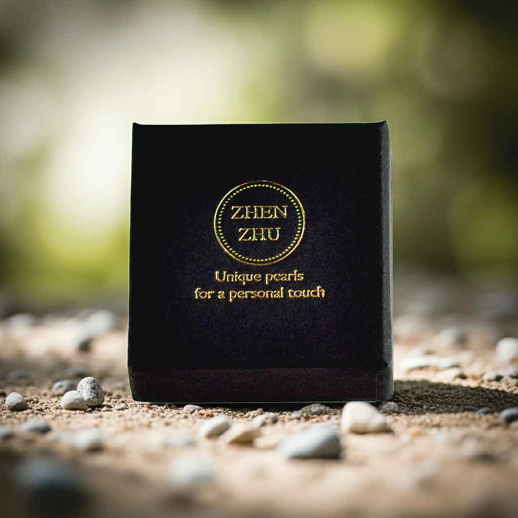 Klein zwart sieraden doosje met gouden logo Zhen Zhu met zand en kiezels