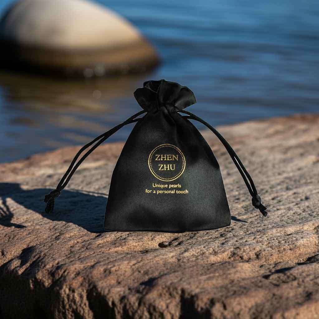 Zwart satijnen sieraden zakje met gouden logo Zhen Zhu met steen en water