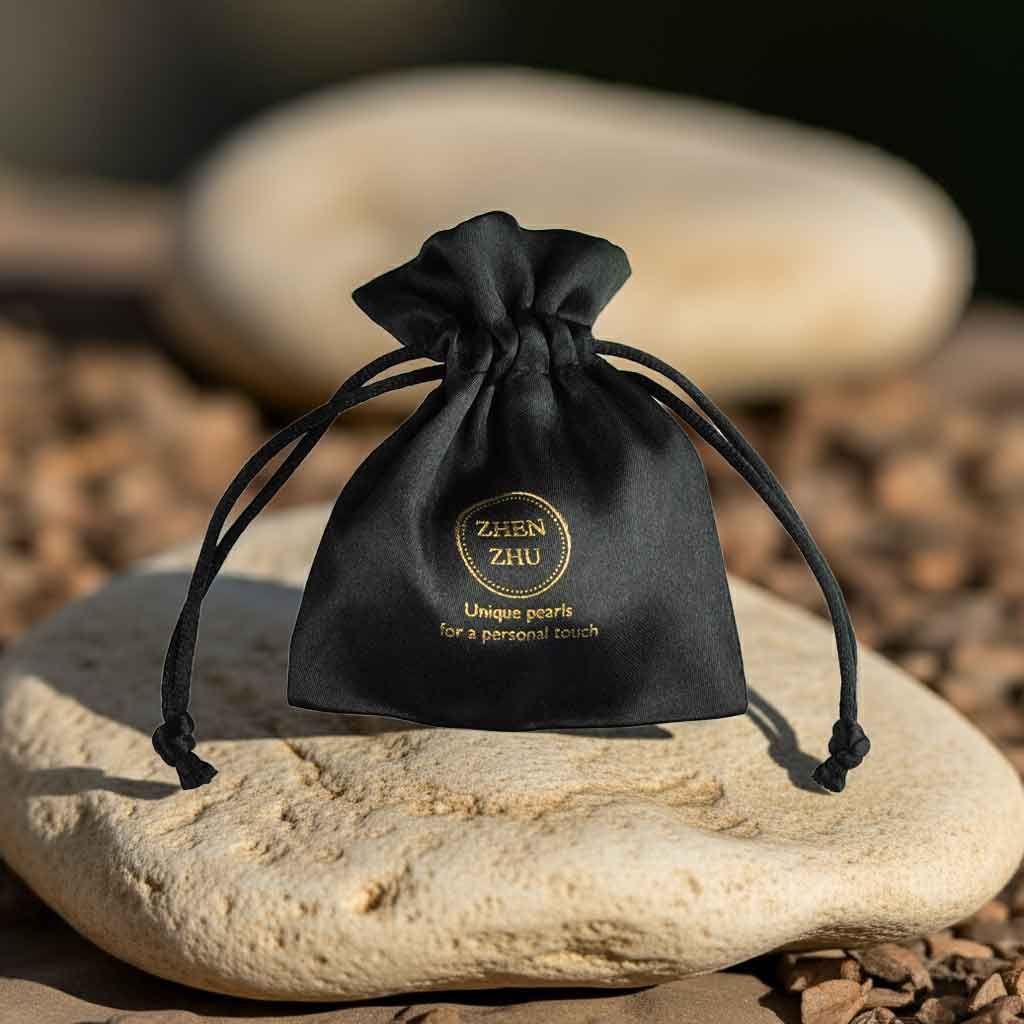 Sieradenzakje met gouden logo van Zhen Zhu liggend op beige steen