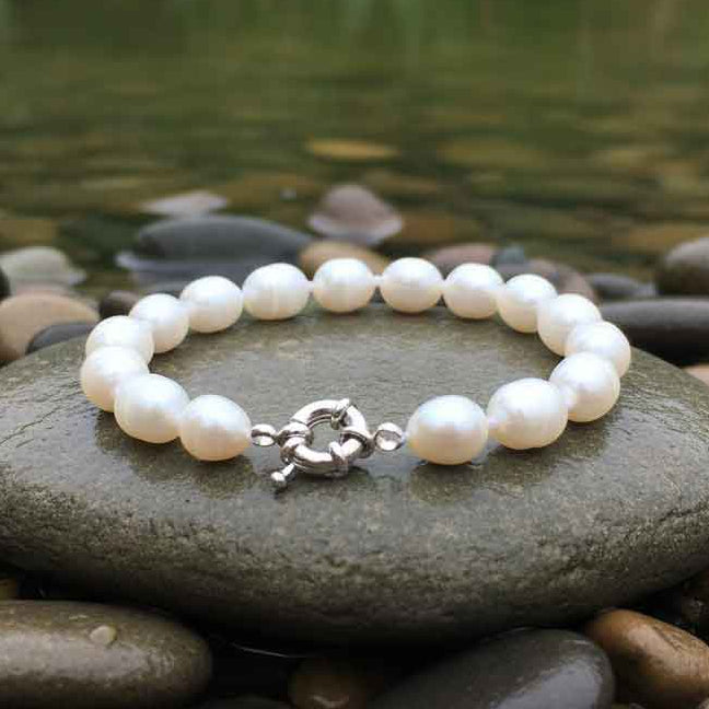 Wit zoetwater parel armband liggend op steen bij water | Wirra