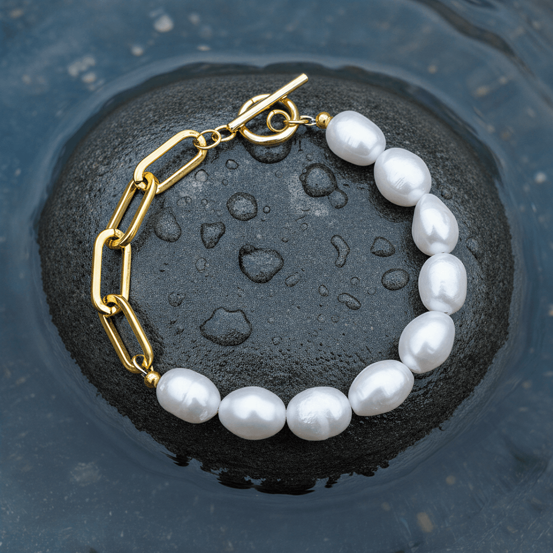 Zoetwater parel armband met witte parels en goud edelstaal liggend op steen in water | Baudine