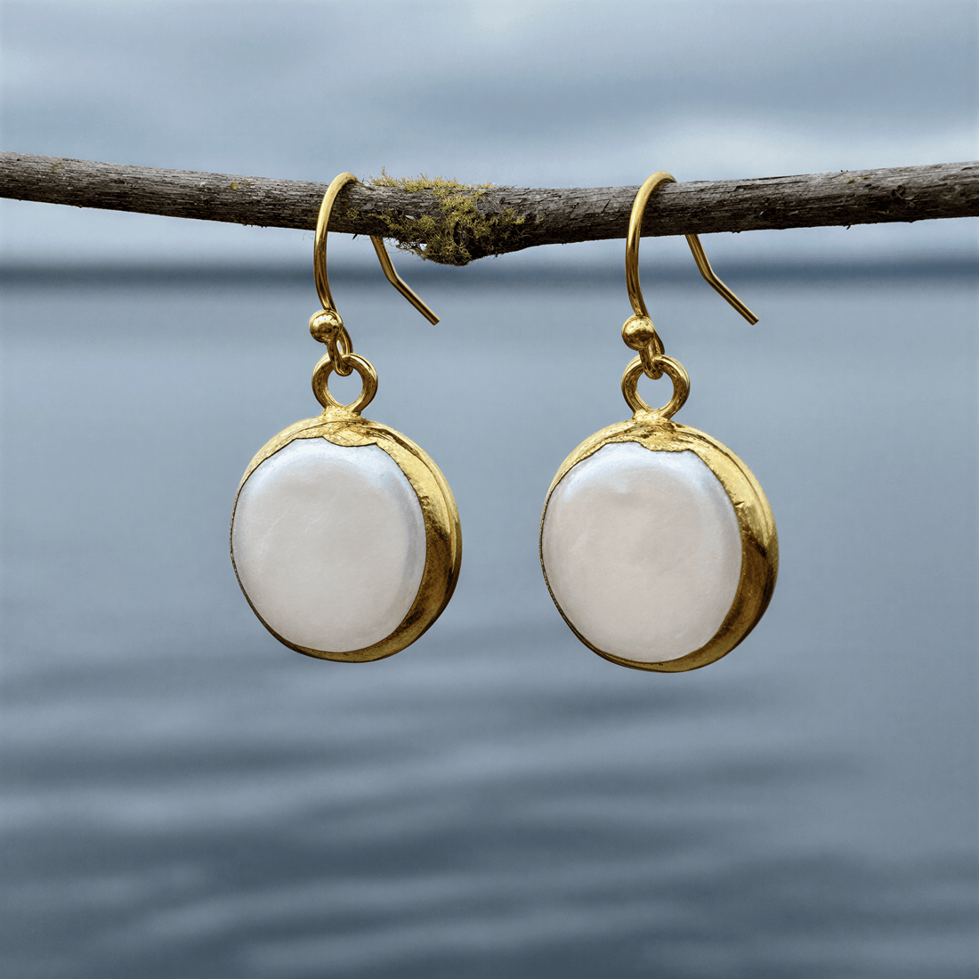 Witte zoetwater parel oorbellen met goud edelstaal hangend aan takje boven water | One Gold Coin Pearl
