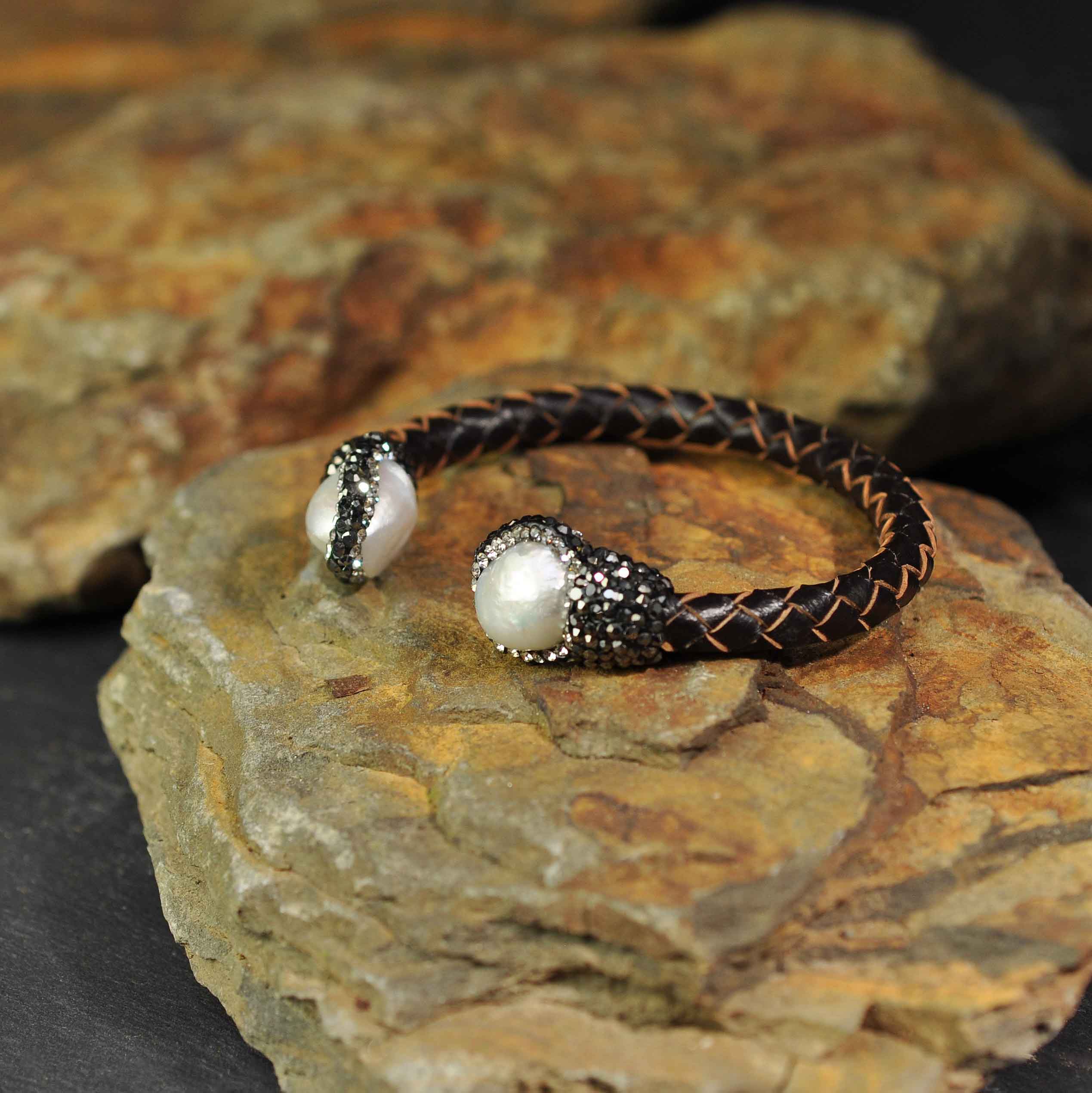 Wit zoetwater parel armband met stras steentjes en bruin gevlochten leer liggend op oranje steen| Bright Pearl Brown Leather Bangle