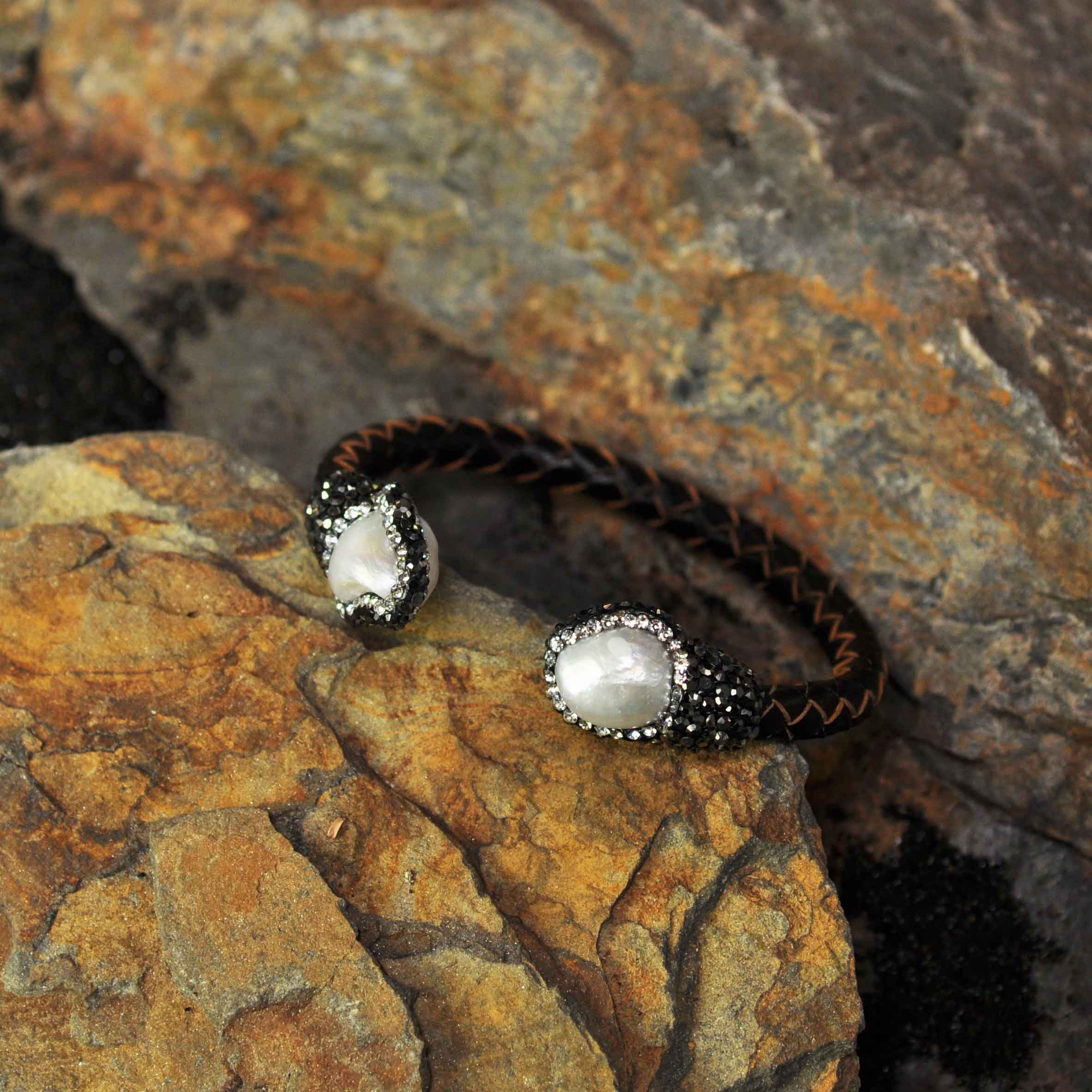 Wit zoetwater parel armband met stras steentjes en bruin gevlochten leer liggend tegen oranje steen| Bright Pearl Brown Leather Bangle