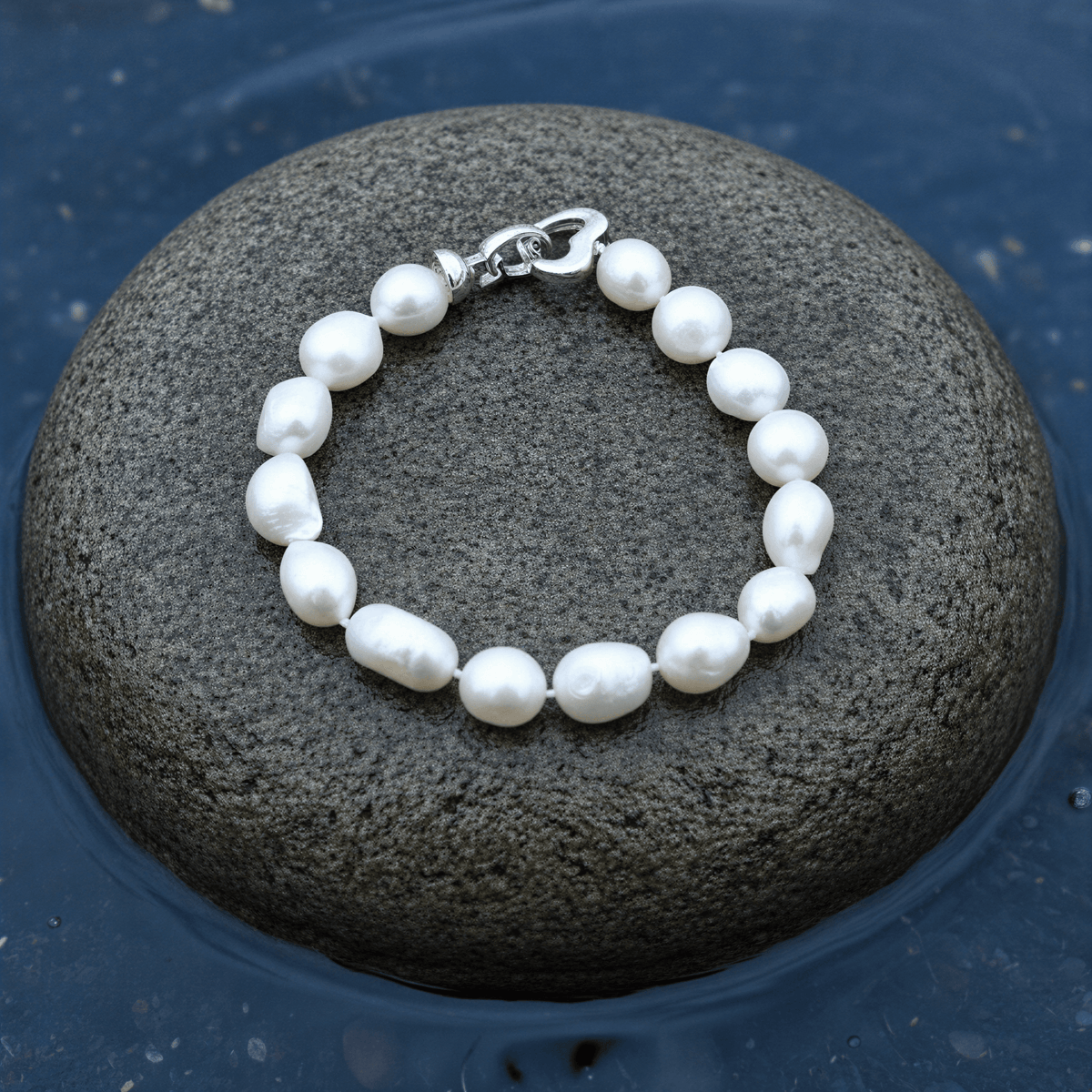 Handgeknoopt parel armband met witte parels liggend op steen in het water | Parel armband Big Round pearl