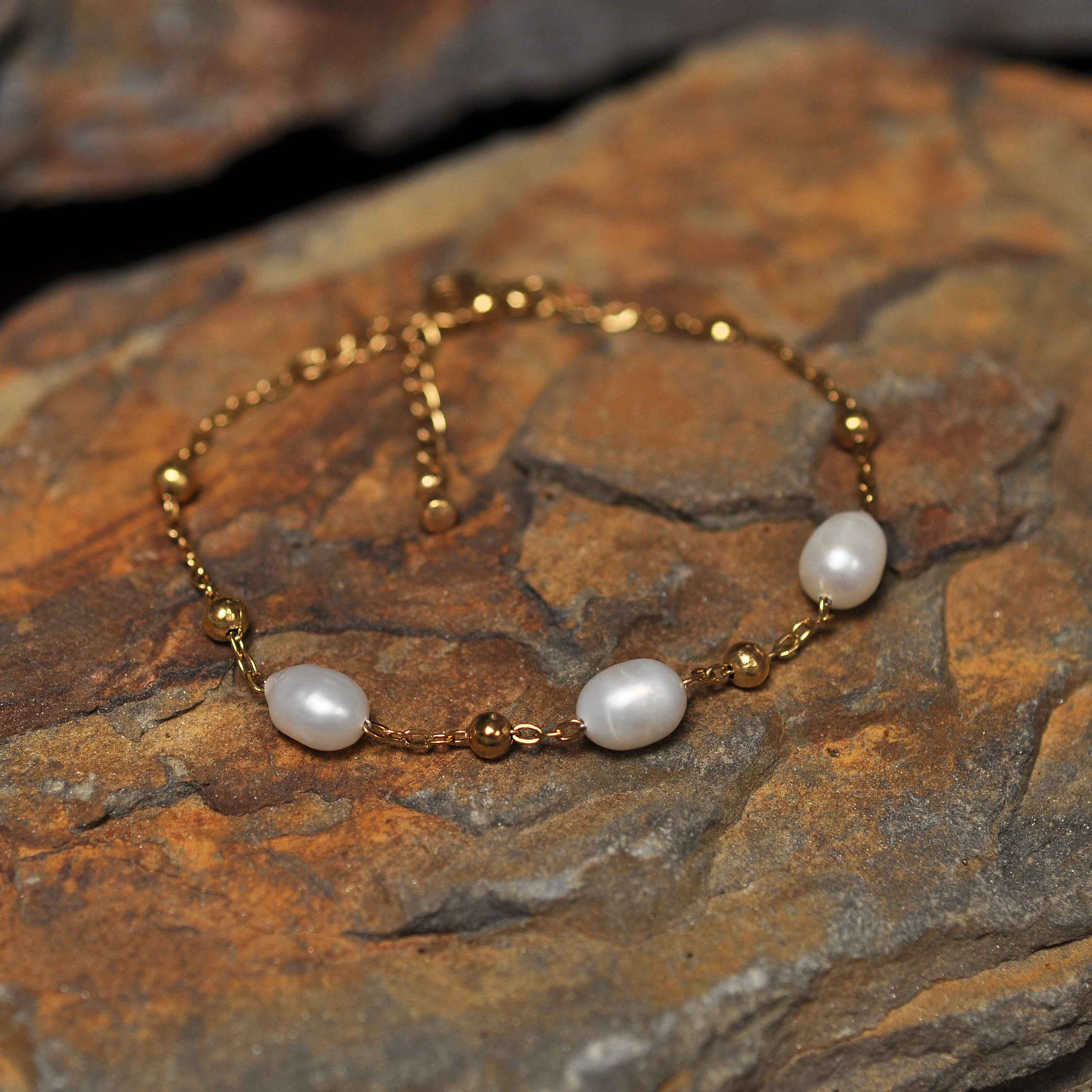 Wit zoetwater parel armband met goud edelstaal liggend op oranje steen | Parel armband Eline Goud