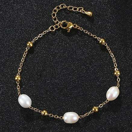 Wit zoetwater parel armband met goud edelstaal liggend op zwart zand | Parel armband Eline Goud