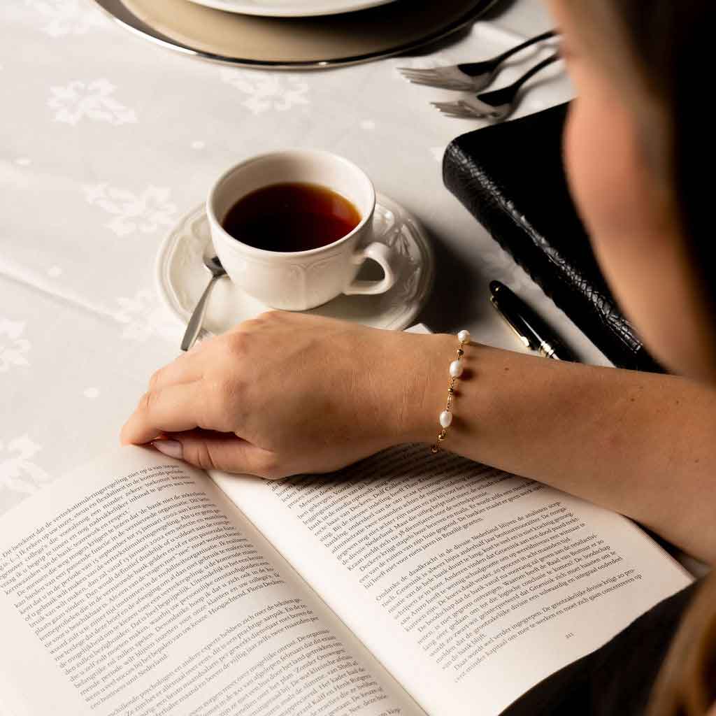 Wit zoetwater parel armband met goud edelstaal met model die boek leest | Parel armband Eline Goud