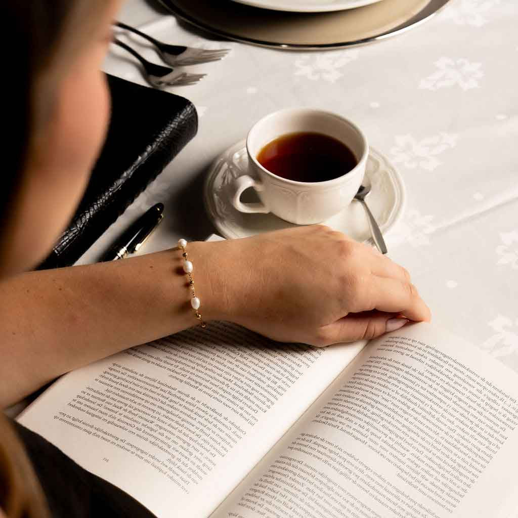 Wit zoetwater parel armband met goud edelstaal met model die boek leest | Parel armband Eline Goud