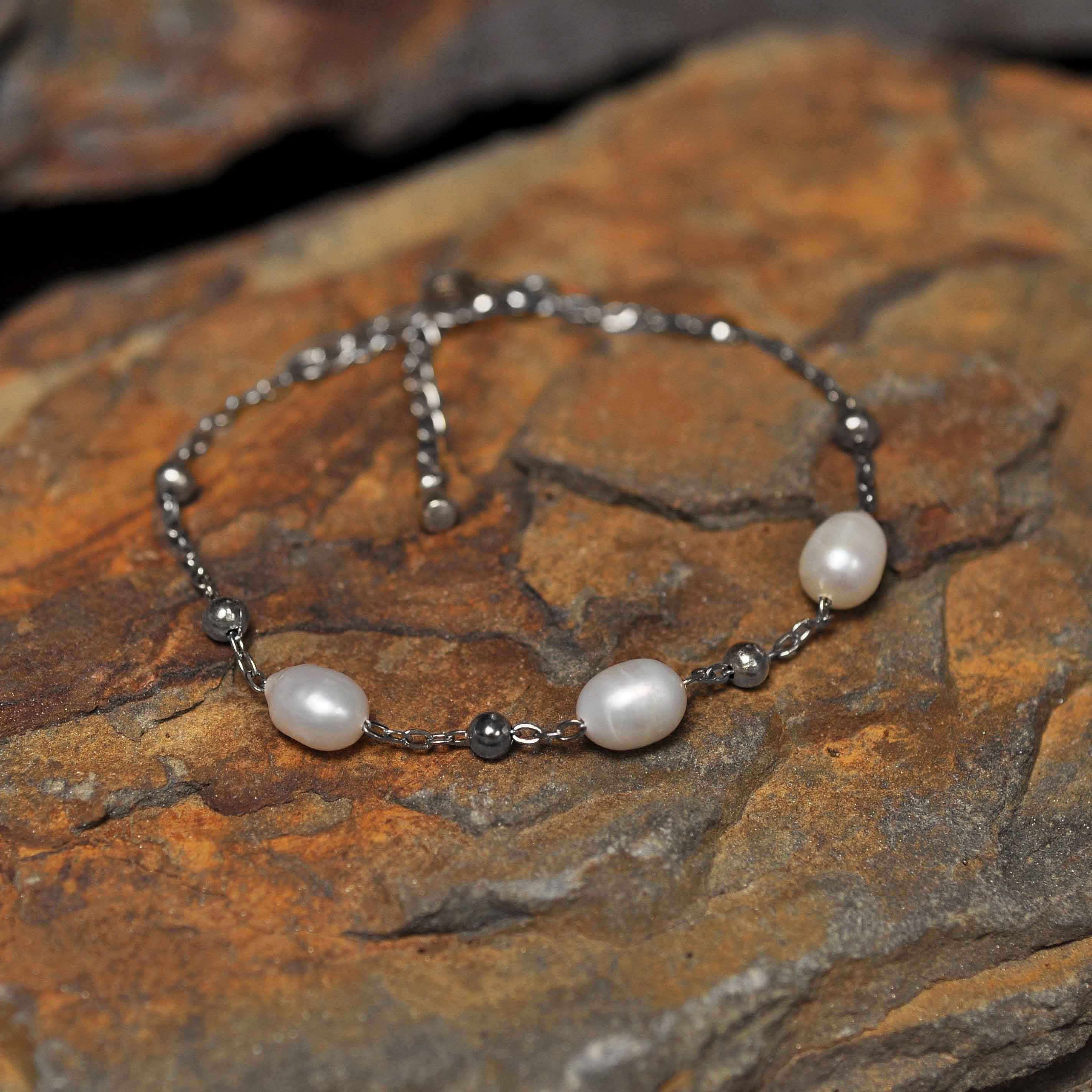 Wit zoetwater parel armband met zilver edelstaal liggend op oranje steen| Parel armband Eline Zilver