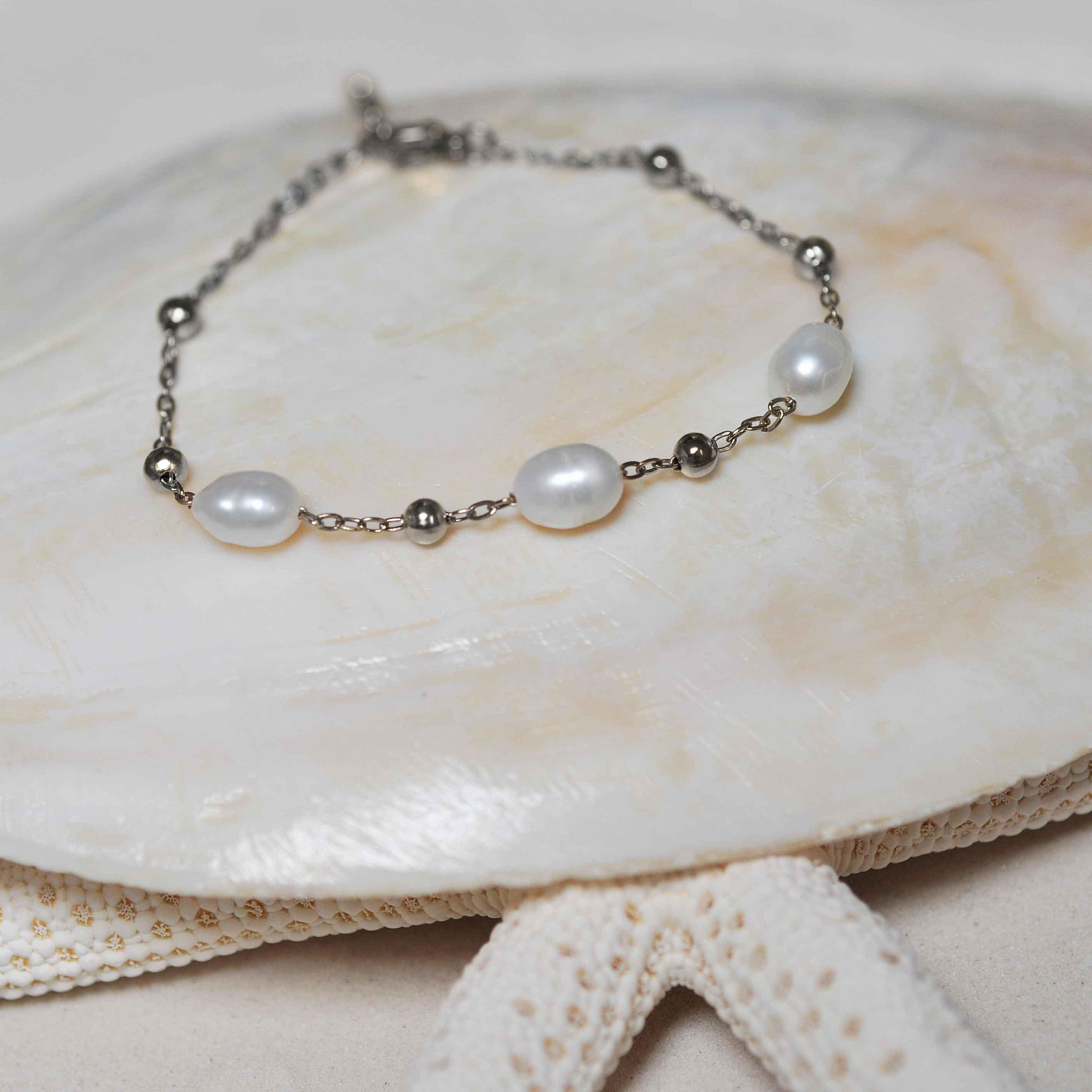 Wit zoetwater parel armband met zilver edelstaal liggend op schelp | Parel armband Eline Zilver