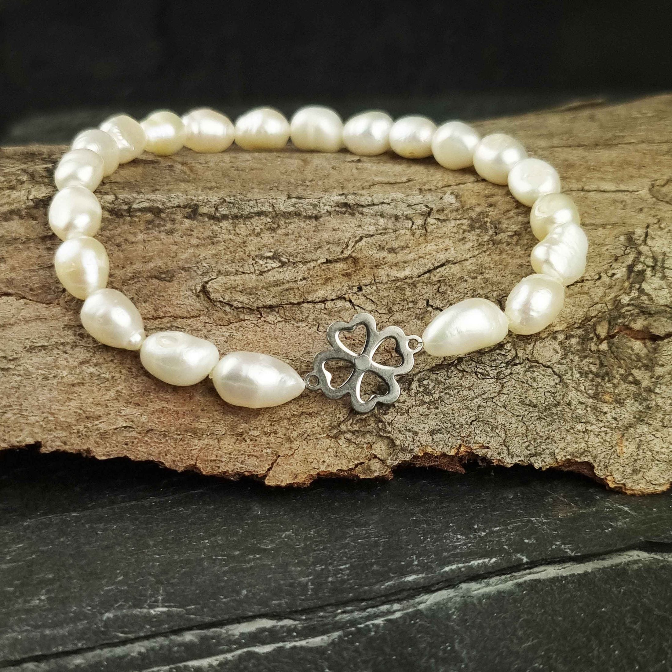 Wit zoetwater parel armband met een klavertje 4 van zilver edelstaal liggend op hout | Good Luck Groot Klavertje 4