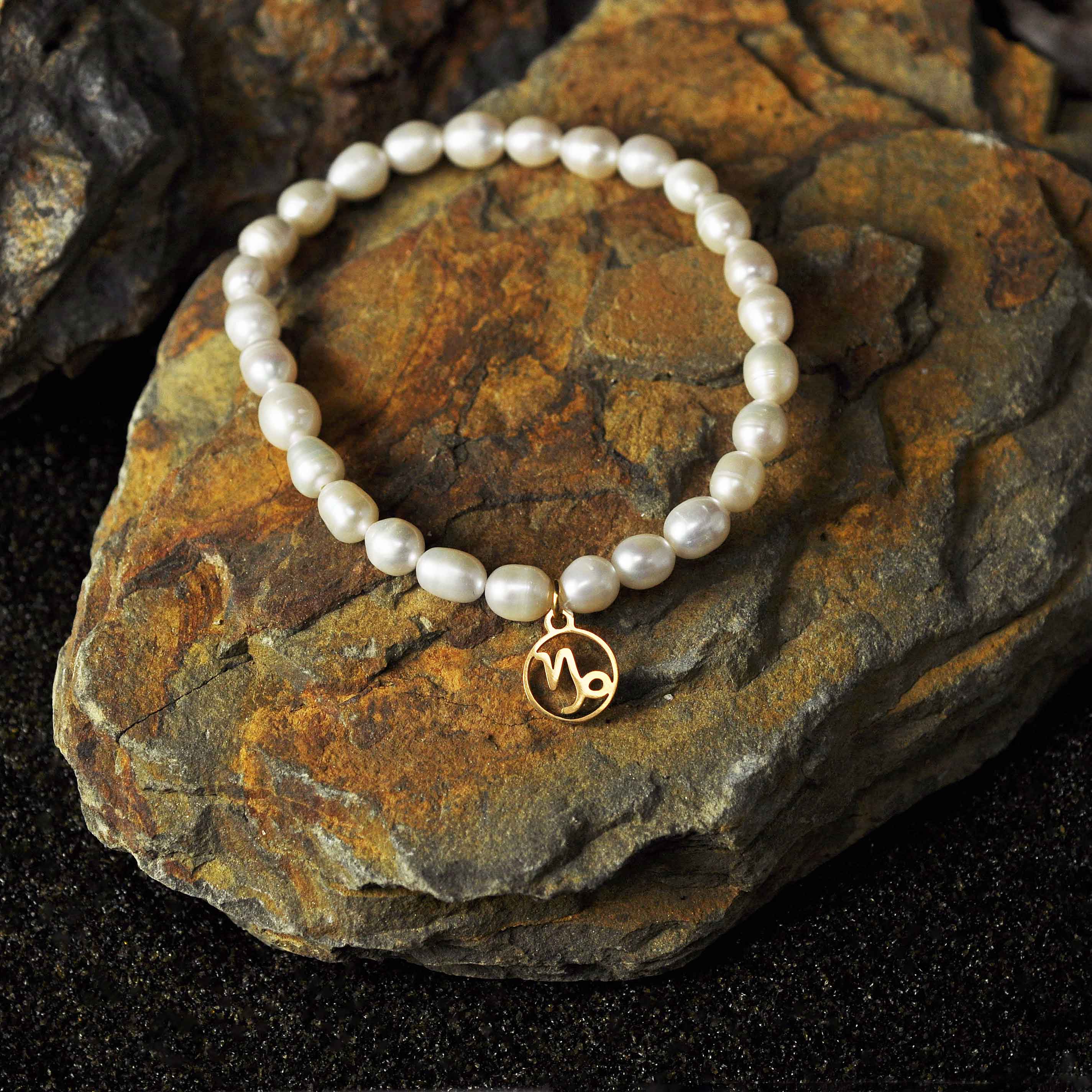 Wit parel armband met gouden edelstalen symbool sterrenbeeld steenbok liggend op steen | Parel armband Gouden
